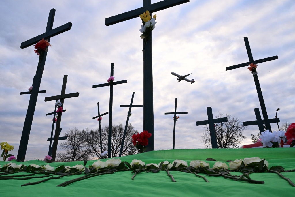 A commercial airplane taking off from Ronald Reagan International Airport passes a memorial near the airport in February 2025