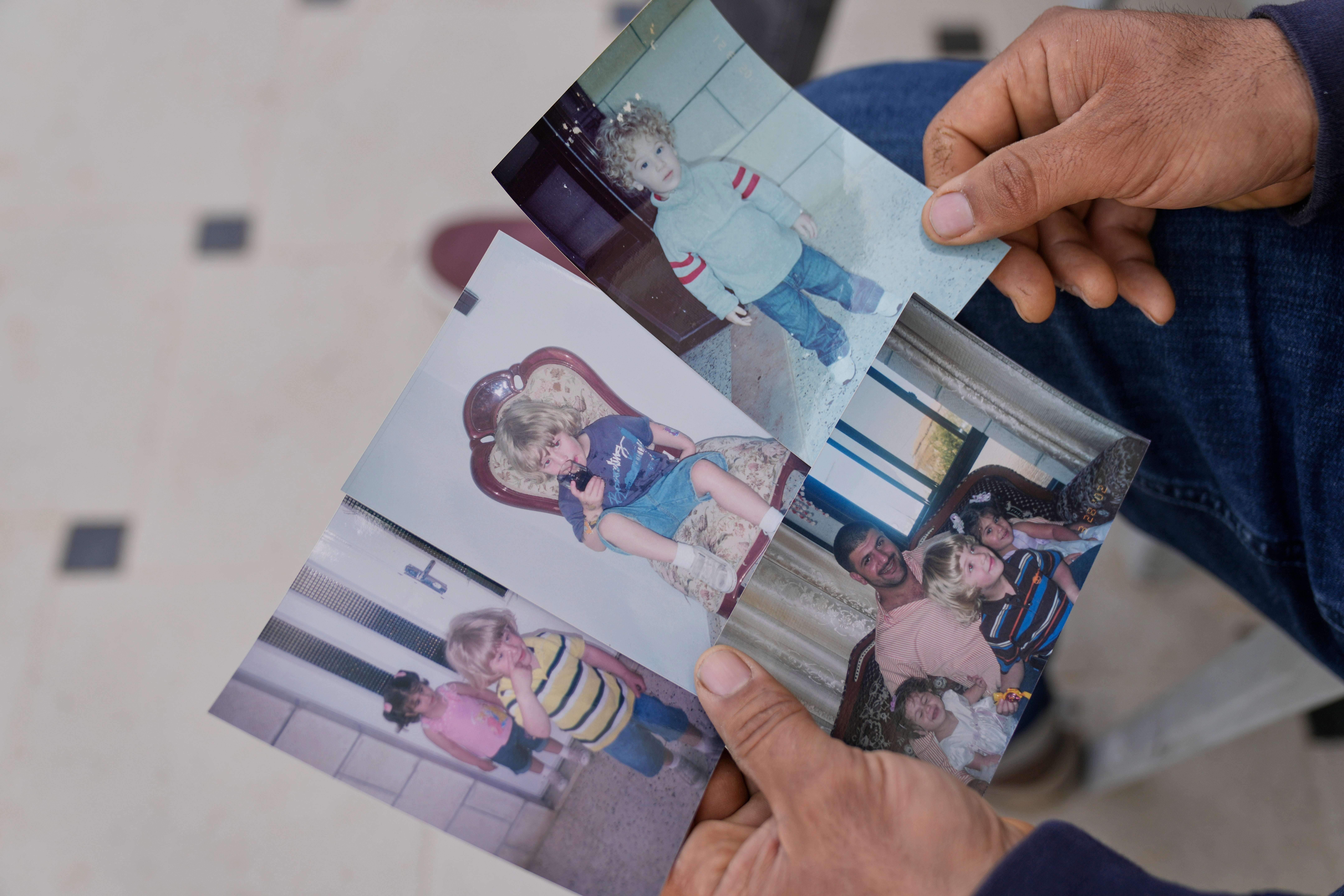 Khalid Ahmad holds childhood photos of his son, Waleed Ahmad, at his family home in the West Bank town of Silwad on 26 March 2025