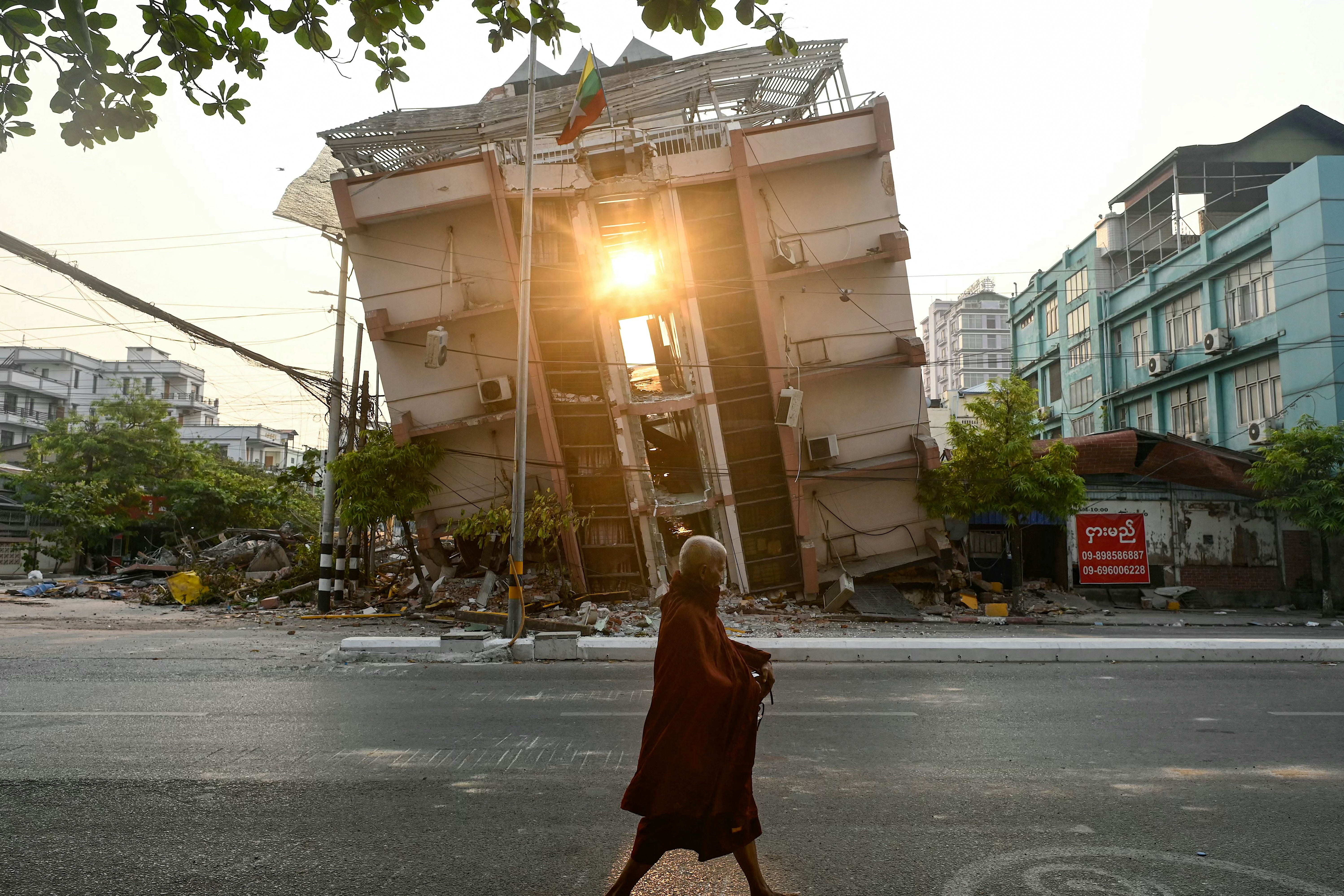 A monk walks past a collapsed building in Mandalay