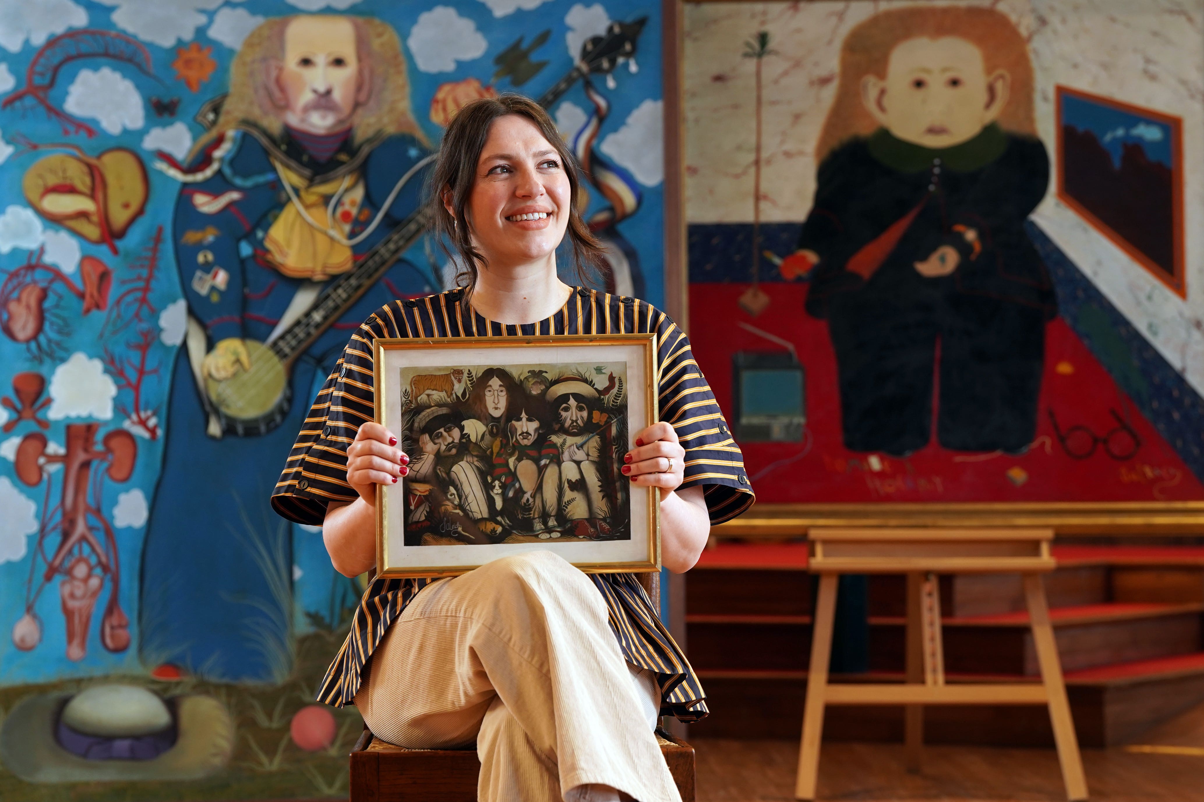 Charlotte Riordan, head of contemporary art at Lyon & Turnbull, holding a painting by the late John Byrne of The Beatles (Stewart Attwood/Lyon & Turnbull/PA)