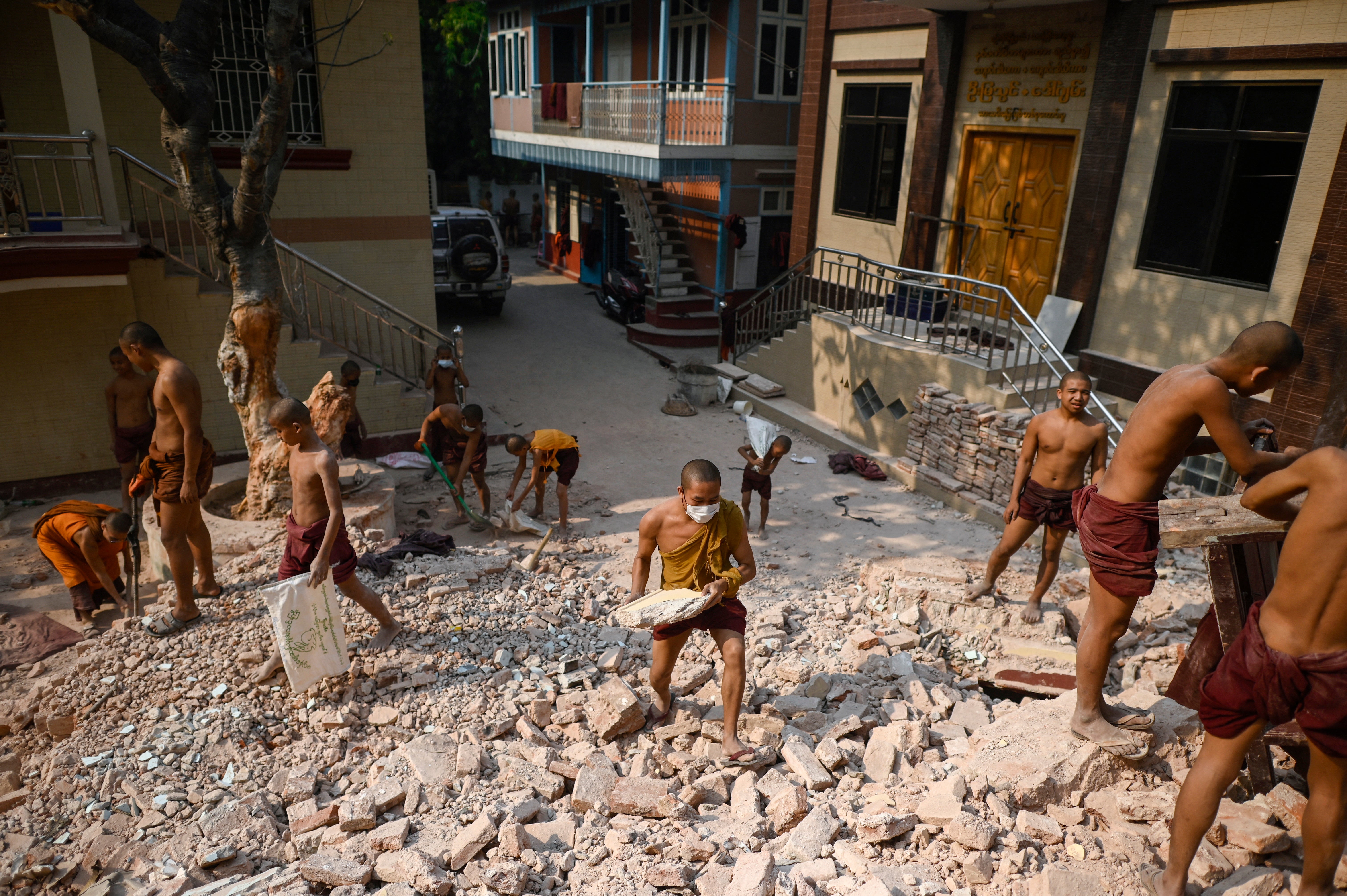 Buddhist monks clear up rubble at the damaged Thahtay Kyaung Monastery in Mandalay