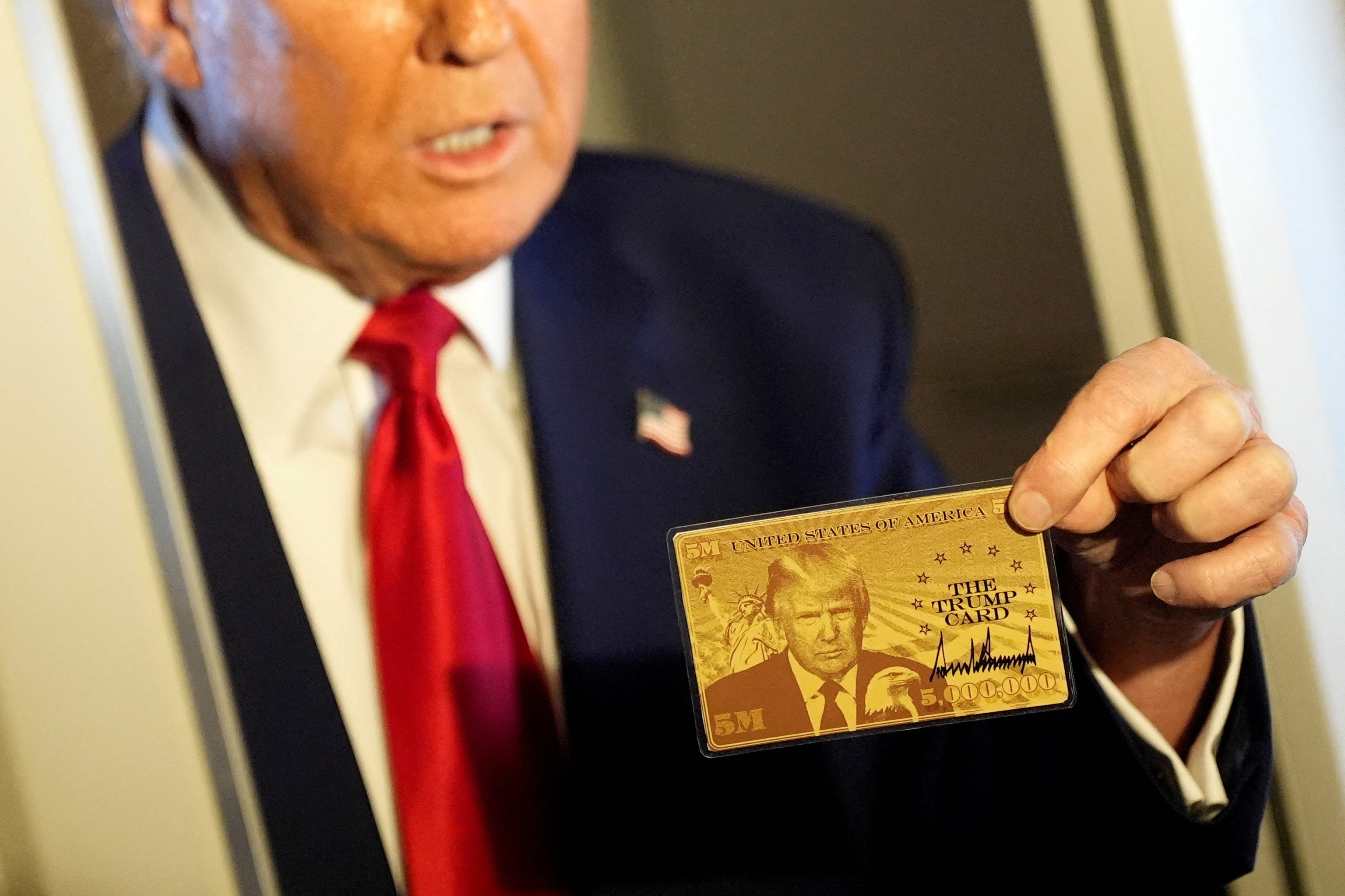 The gold-colored card features Trump’s face on it
