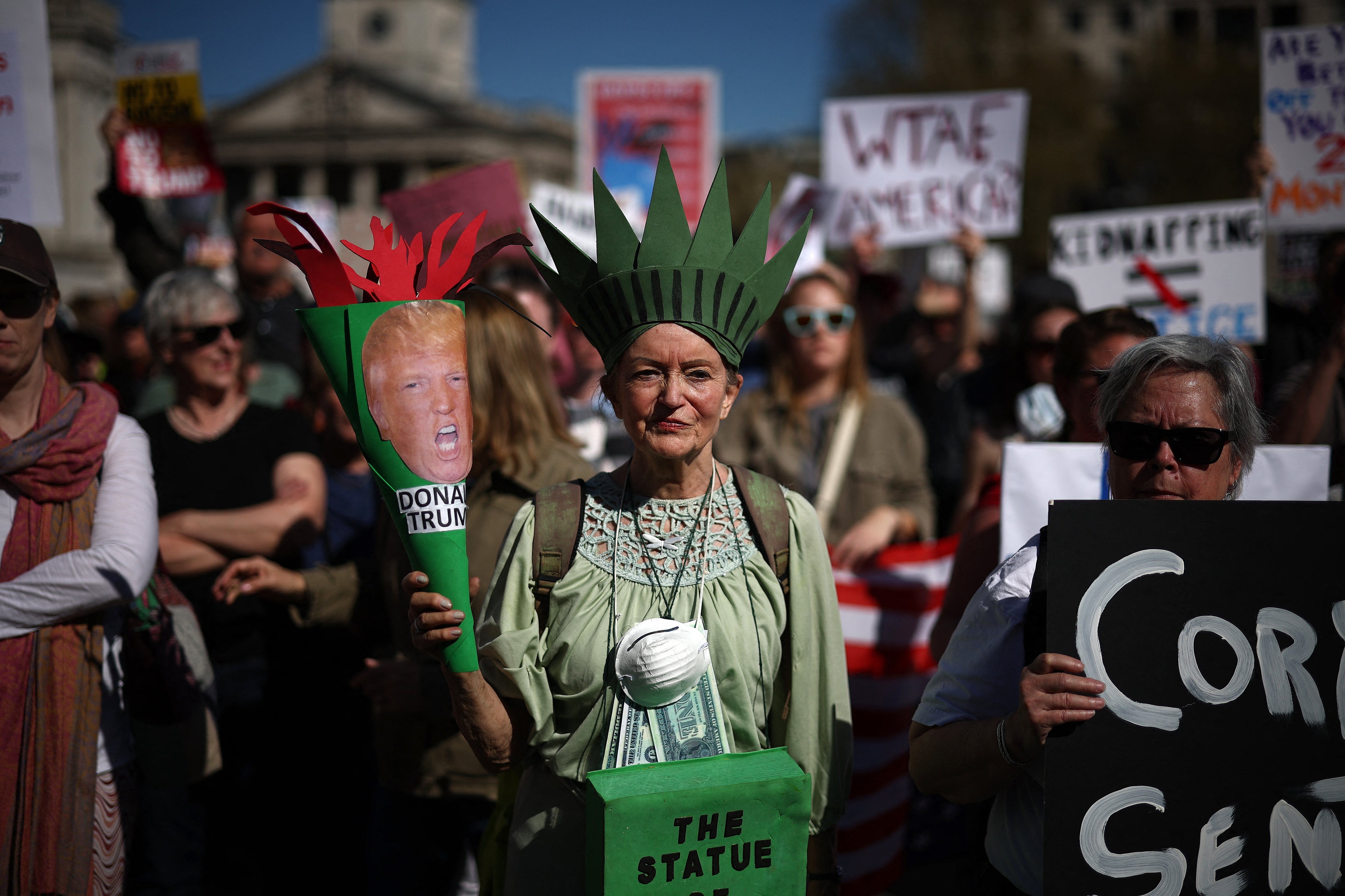 A demonstrator dressed as the Statue of Liberty holds up a placard during a protest in London’s Trafalgar Square