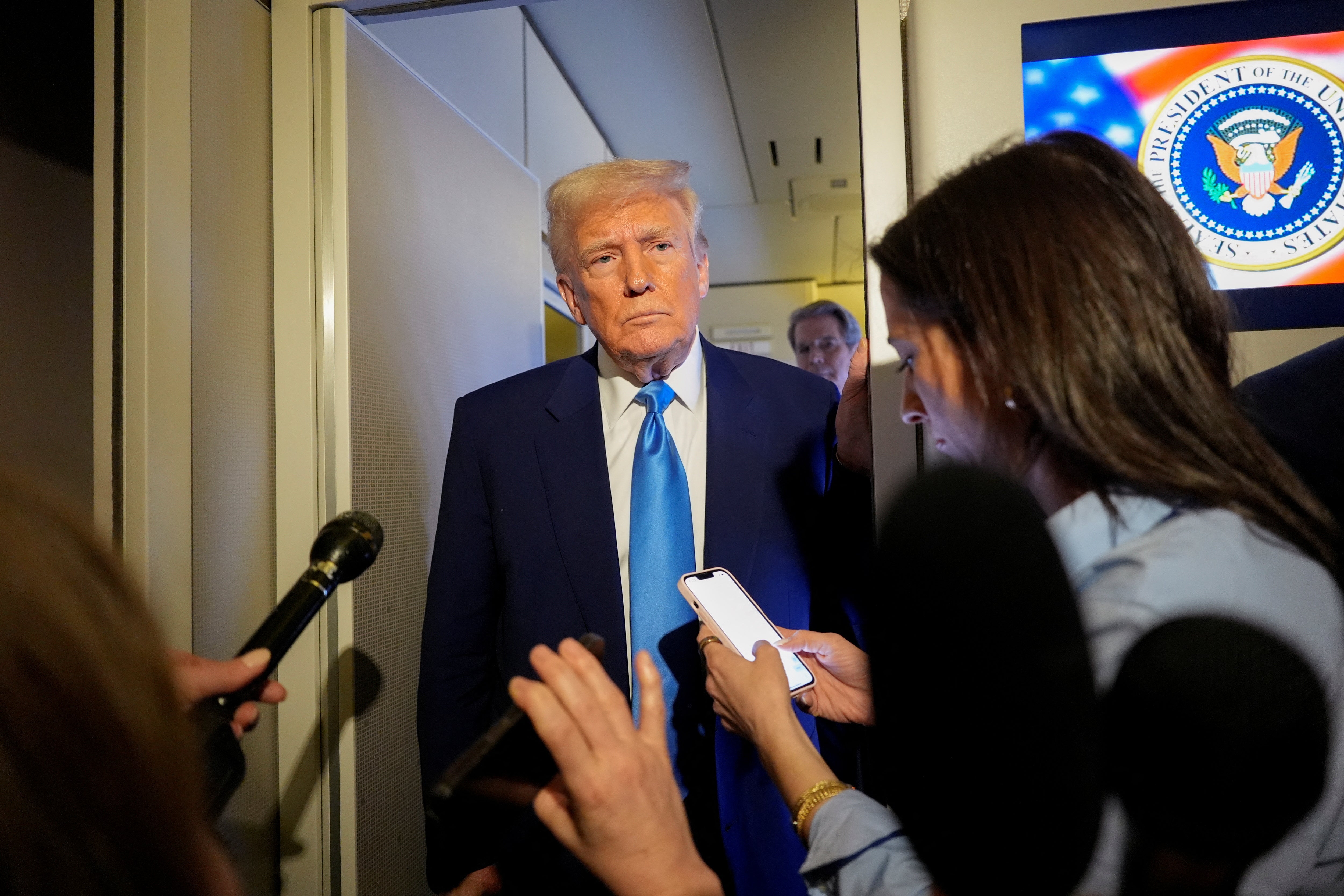 President Donald Trump speaks to the media on Air Force One on Sunday evening as he flies back to Washington, D.C. after a weekend golfing in Florida