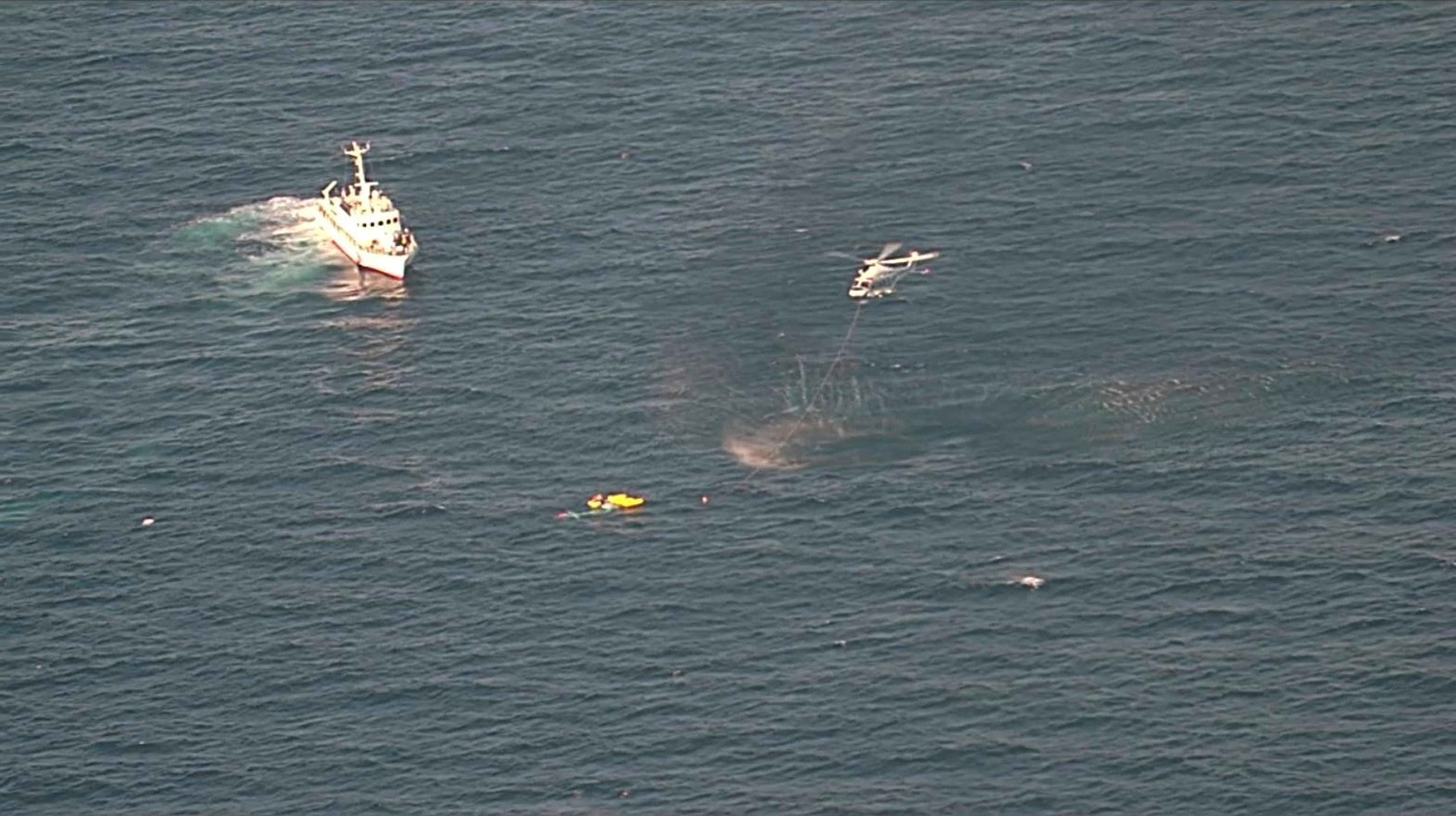 A coast guard vessel and a helicopter assist a rescue operation after a medical transport helicopter fell into the sea in southwestern Japan
