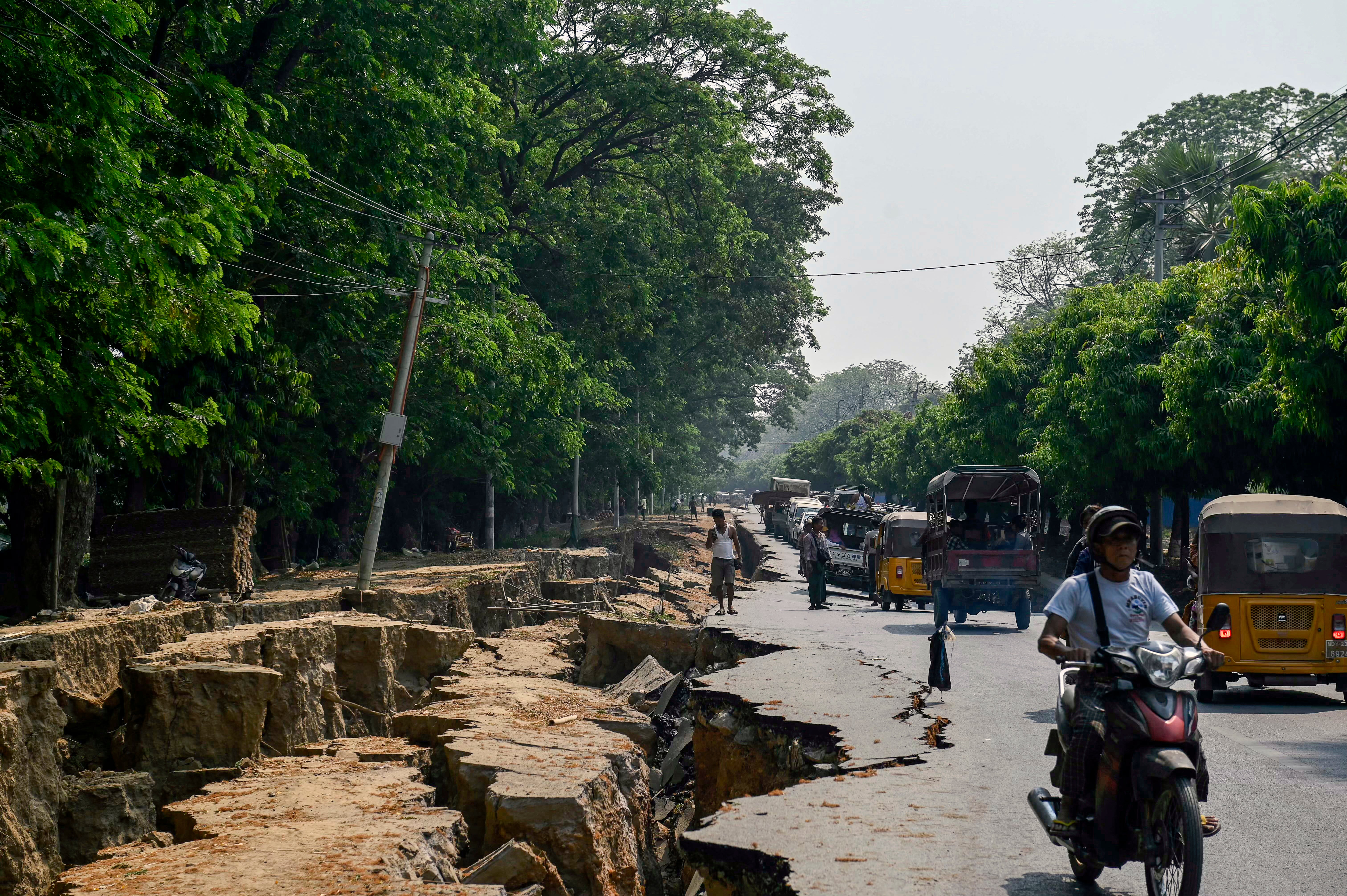 Motorists make their way past a large crack in the ground along Myo Patt Road linking Mandalay and Sagaing township