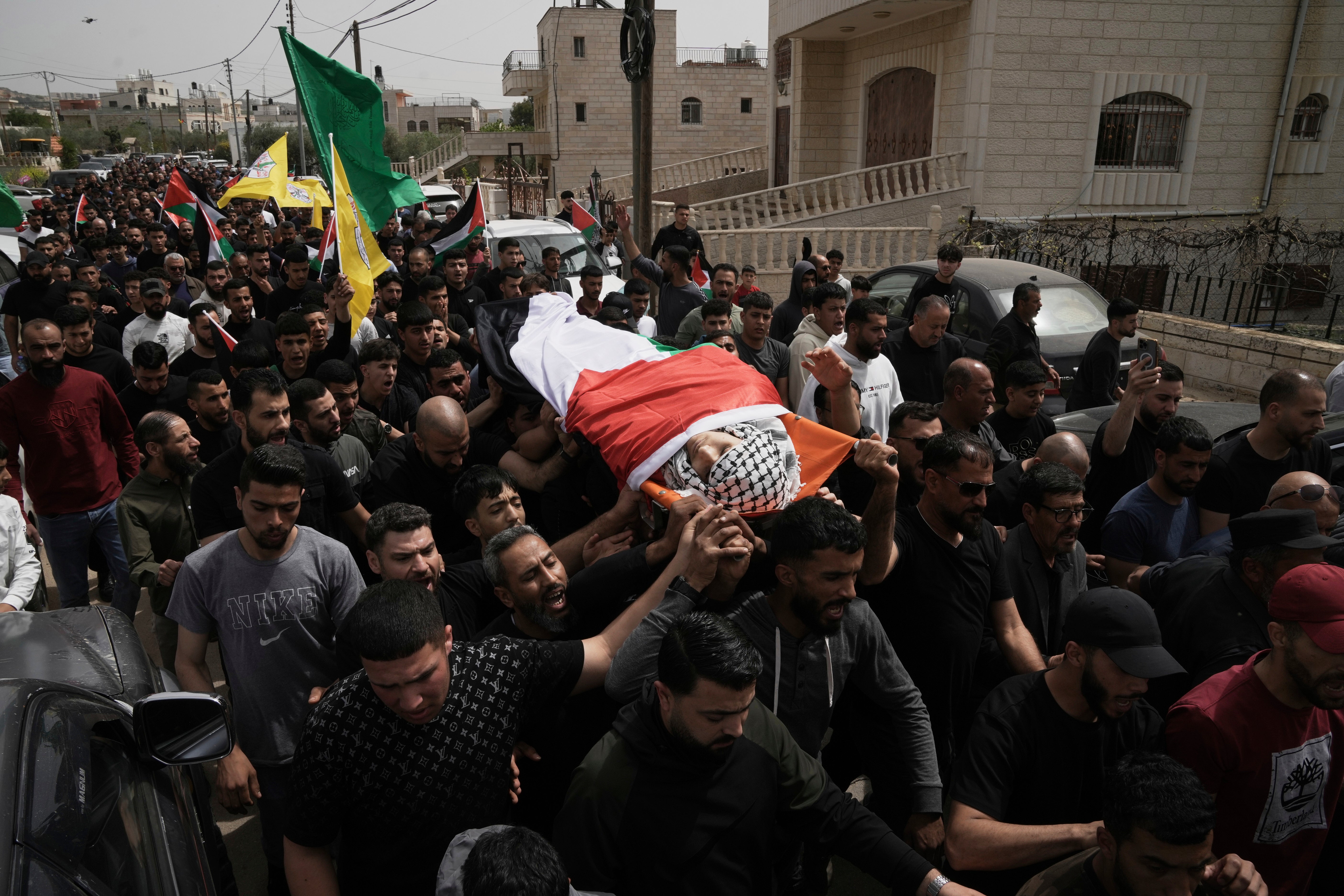 Mourners carry Amer Mohammed Rabee, a 14 year-old Palestinian-American shot by Israeli forces, during his funeral in the West Bank town of Turmus Ayya