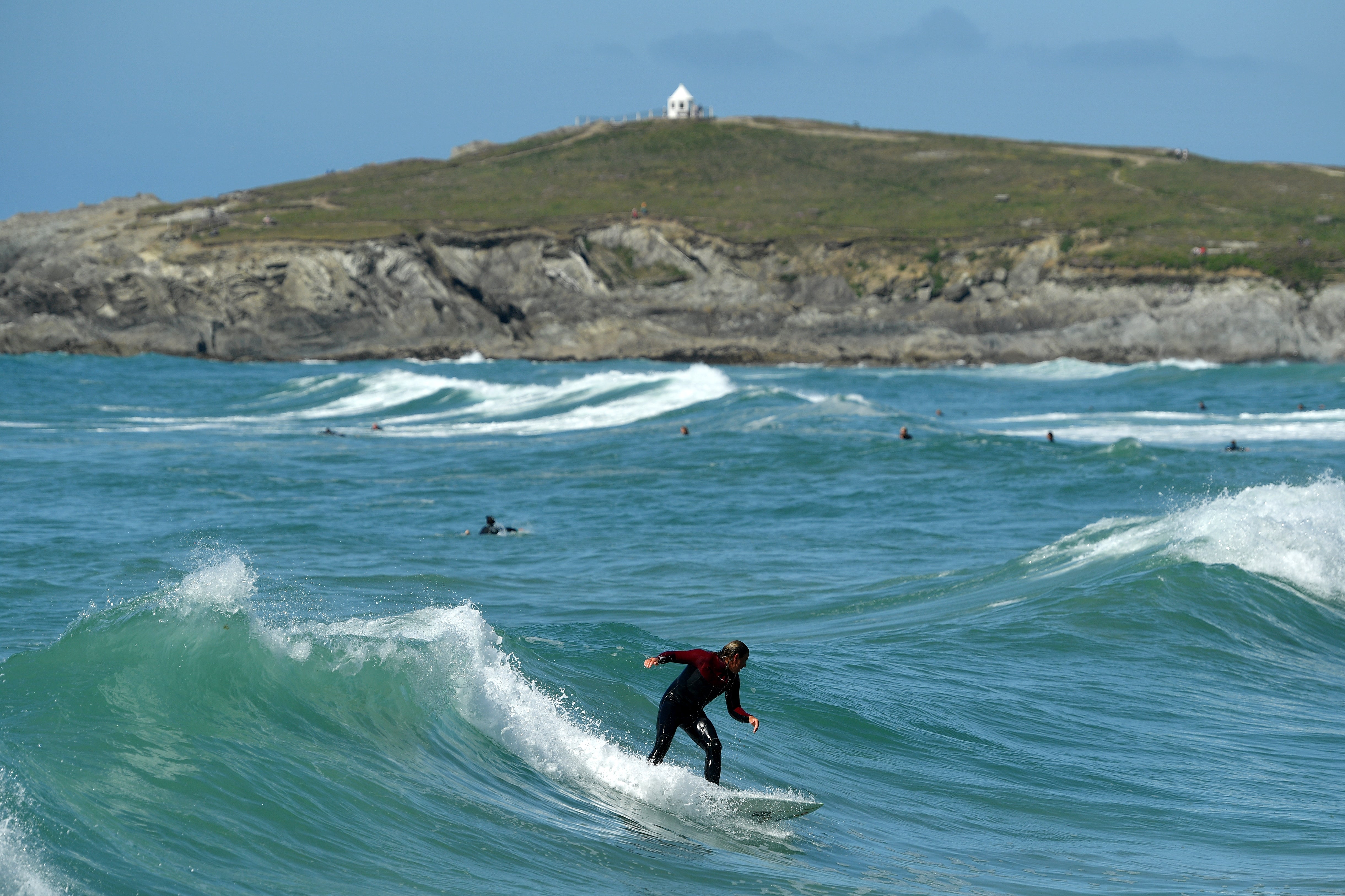 A surfer catches a wave at Fistral Beach in Newquay