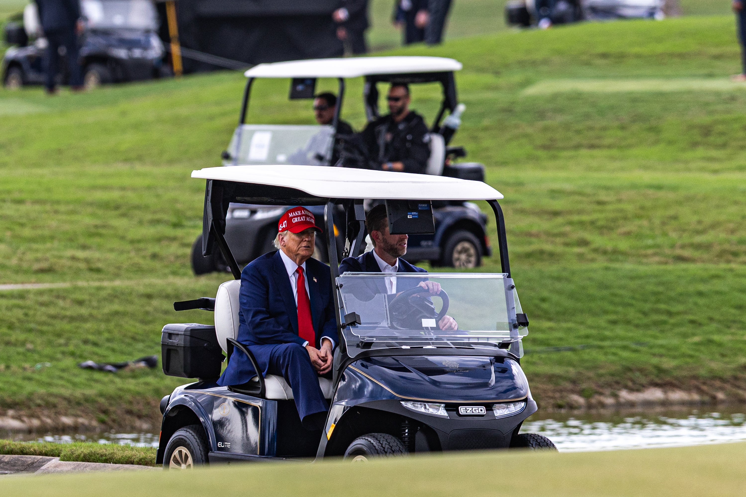Donald Trump and his son Eric Trump drive in a golf cart after arriving on Marine One on the ninth hole during previews for LIV Golf Miami at Trump National Doral Miami on April 3, 2025. The president has faced criticism for hitting the links amid a market meltdown in response to his tariffs