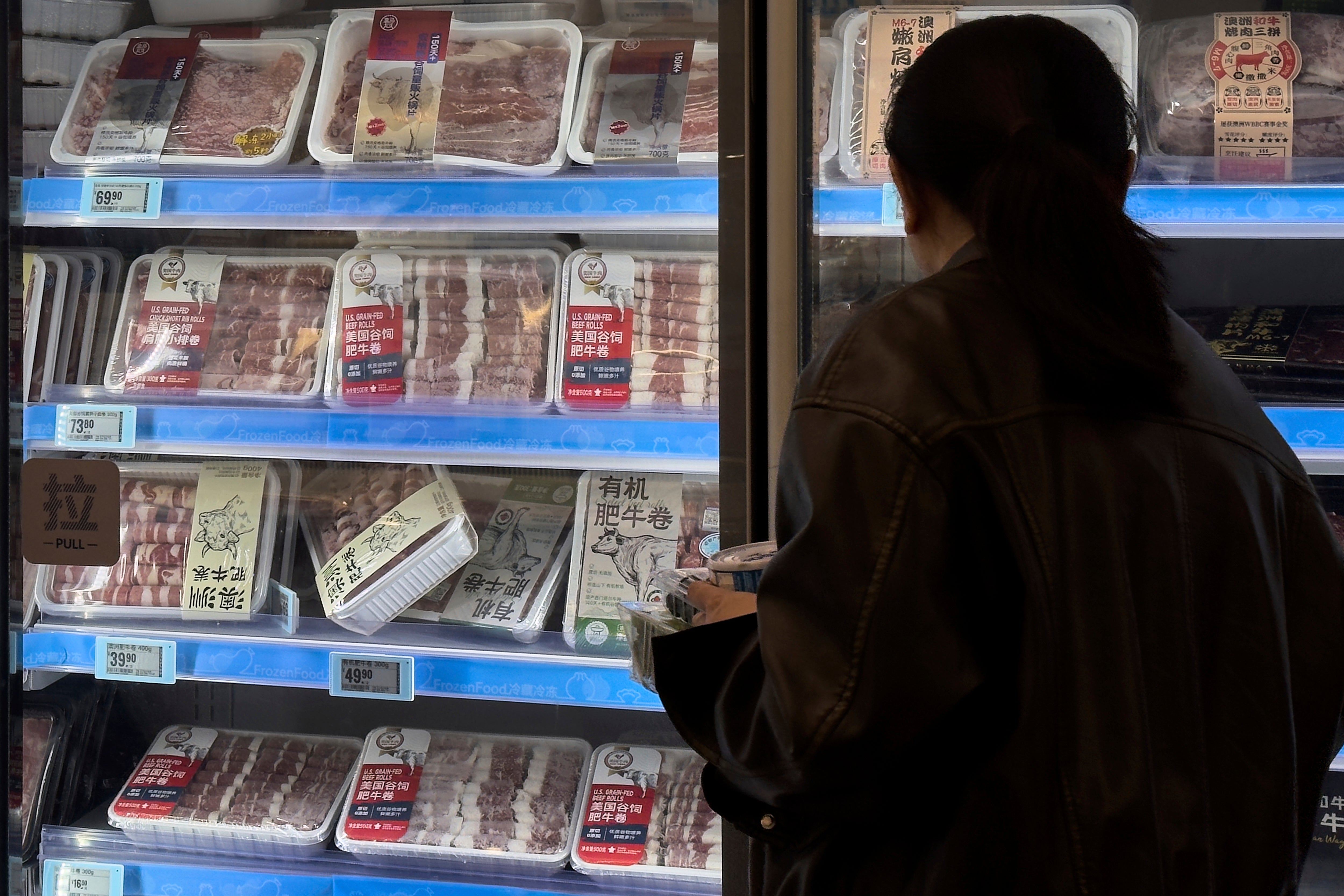 A woman looks at the imported frozen beefs from the United States and Australia on display for sale at the Hema supermarket, in Beijing