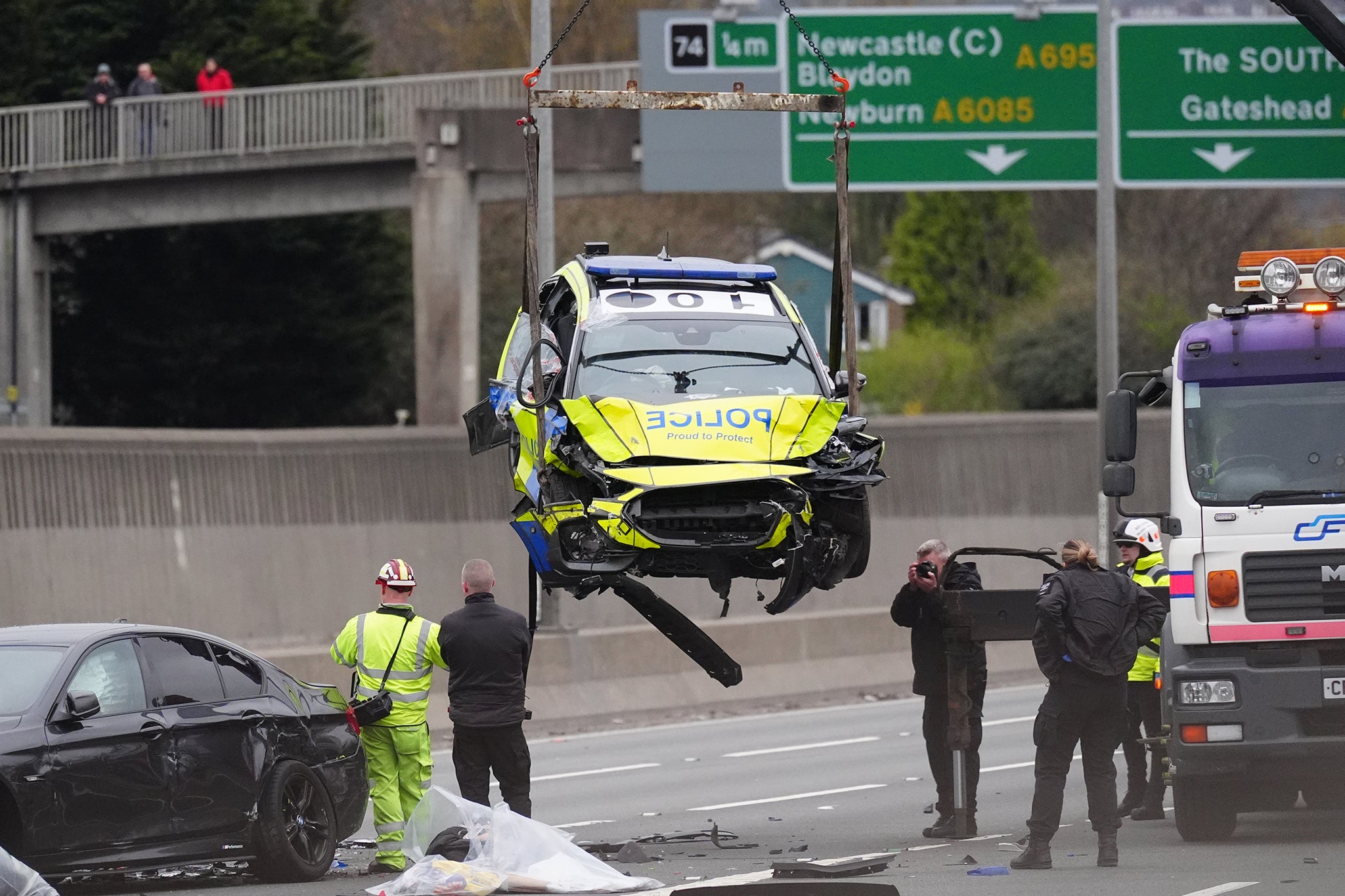 One of the badly damaged police vehicles is lifted off the A1