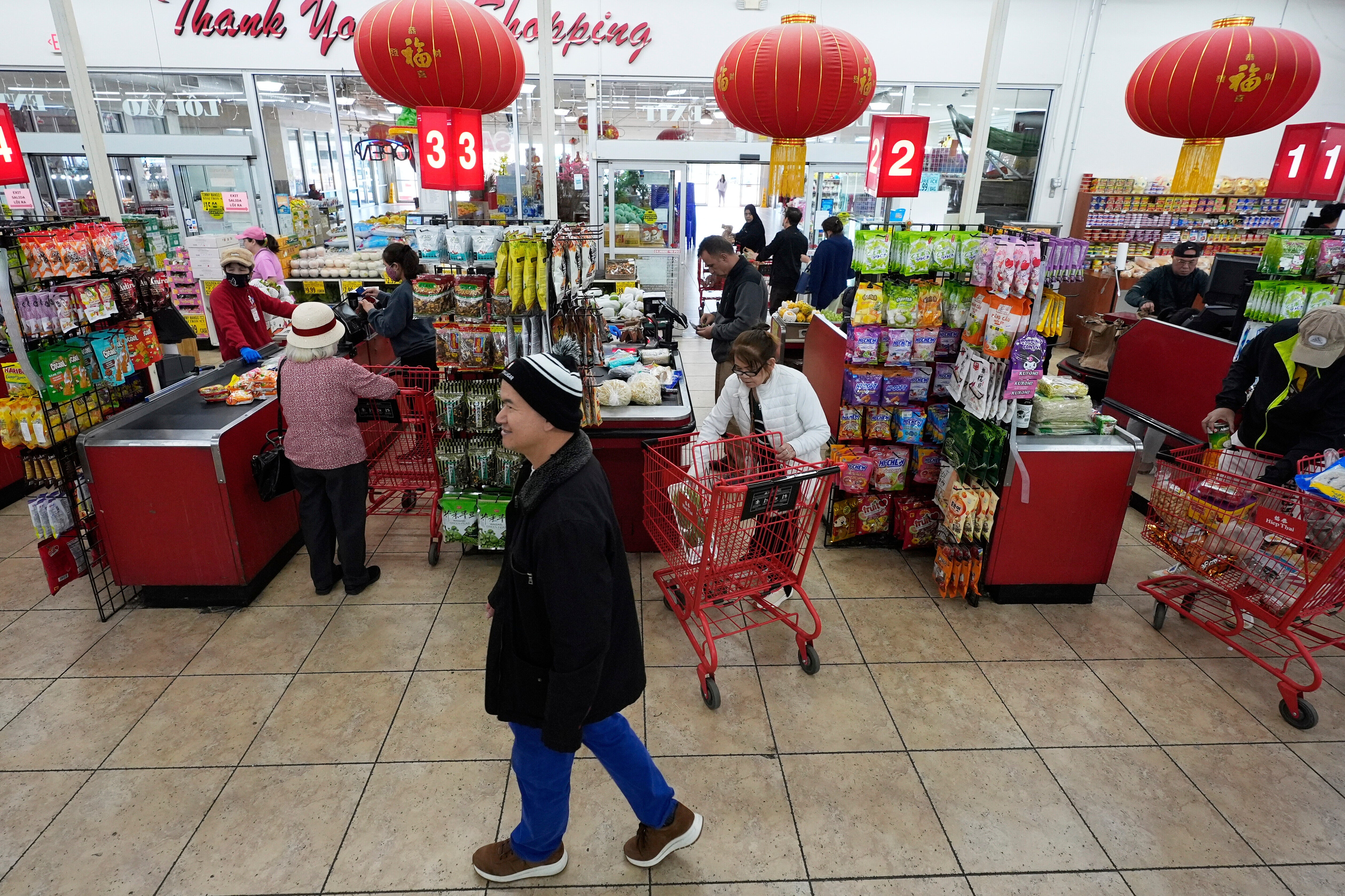 Chan 'Bill' Vuu, owner of Hiep Thai grocery store, walks past cashiers and customers at his family's store in Garland, Texas