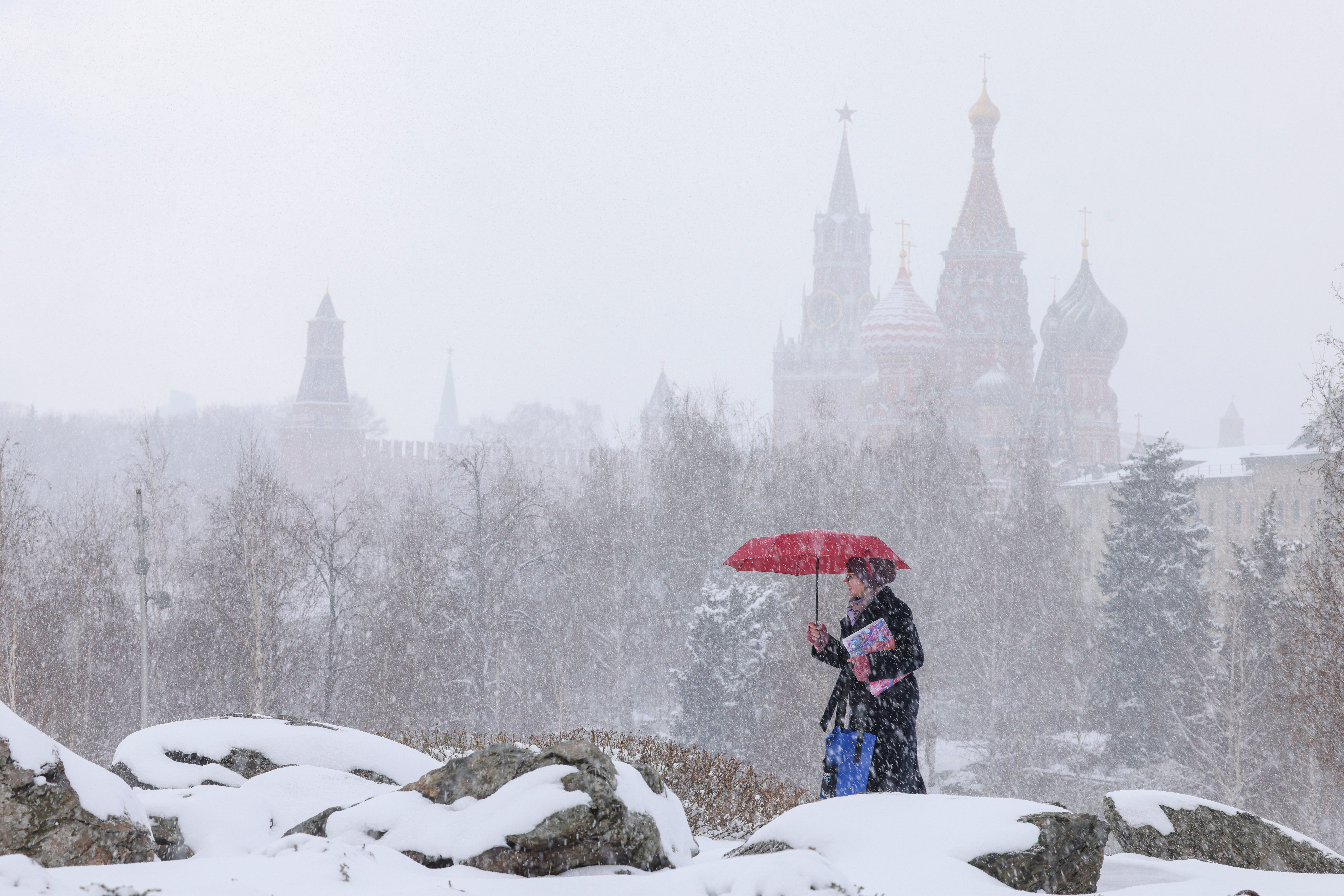 A woman walks in front of the Kremlin during a snowfall in Moscow, Russia, 09 April 2025