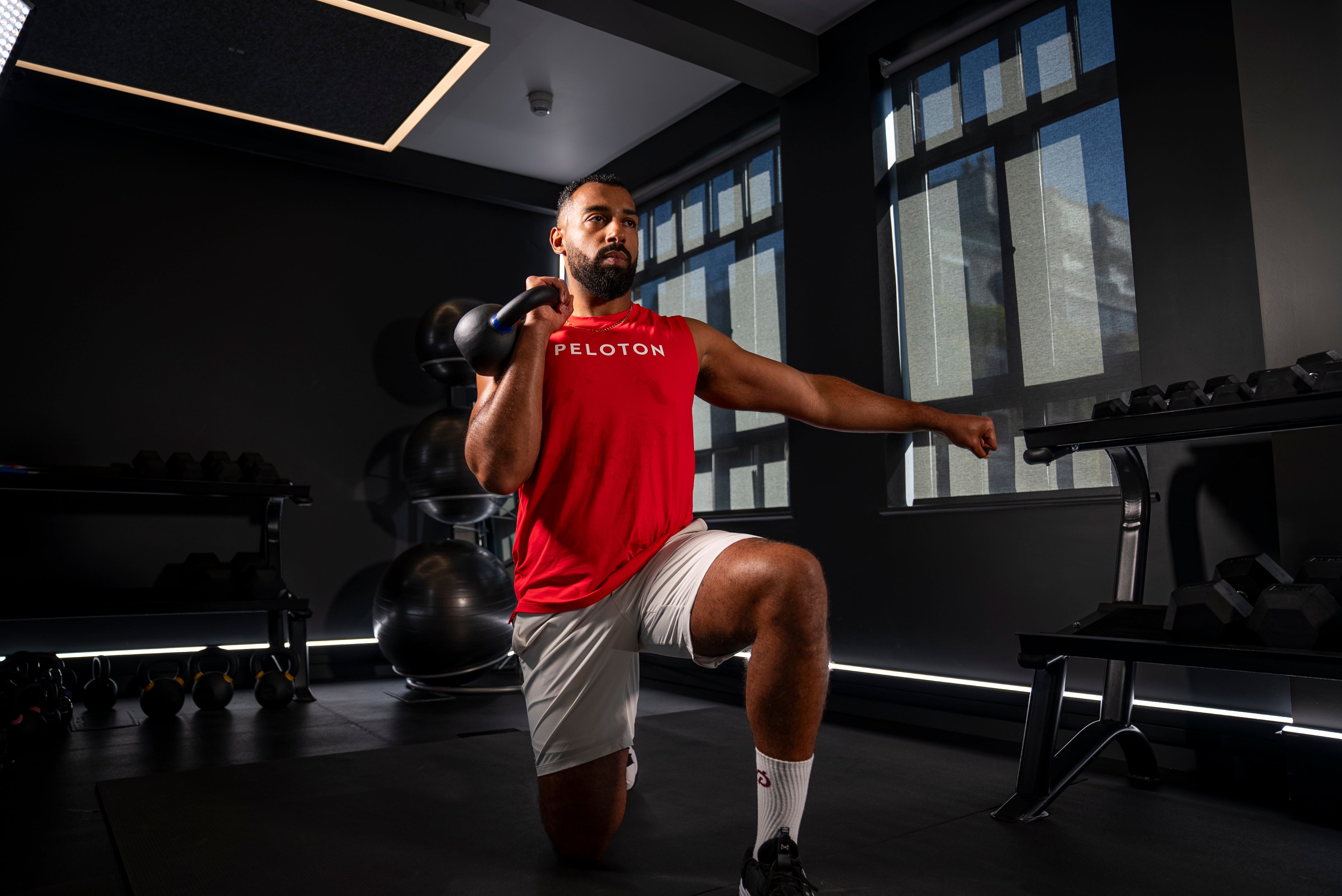 Peloton instructor Jermaine Johnson demonstrating a half-kneeling press