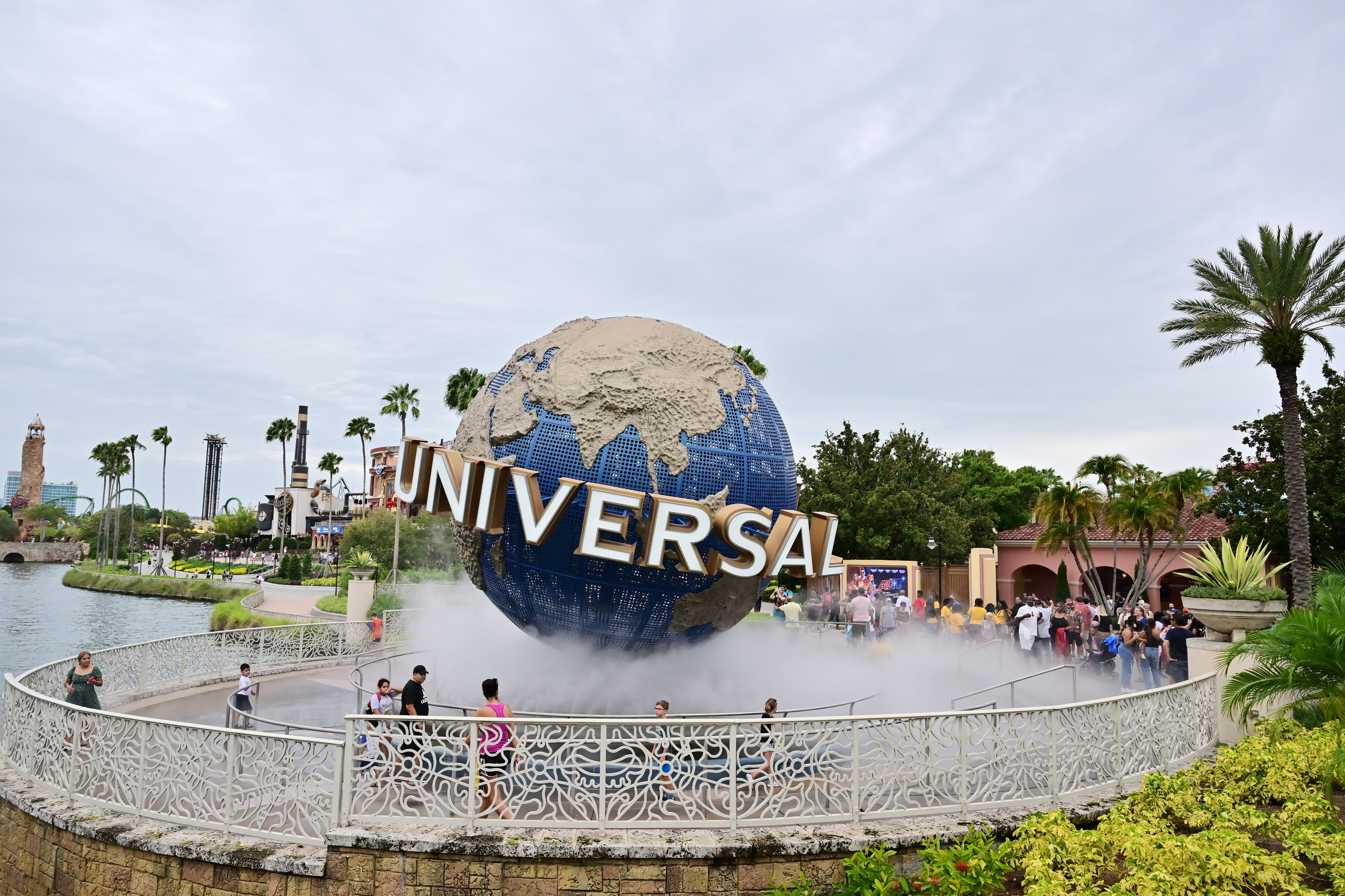 Guests cool off under a water mist by the globe at Universal Studios Florida in Orlando