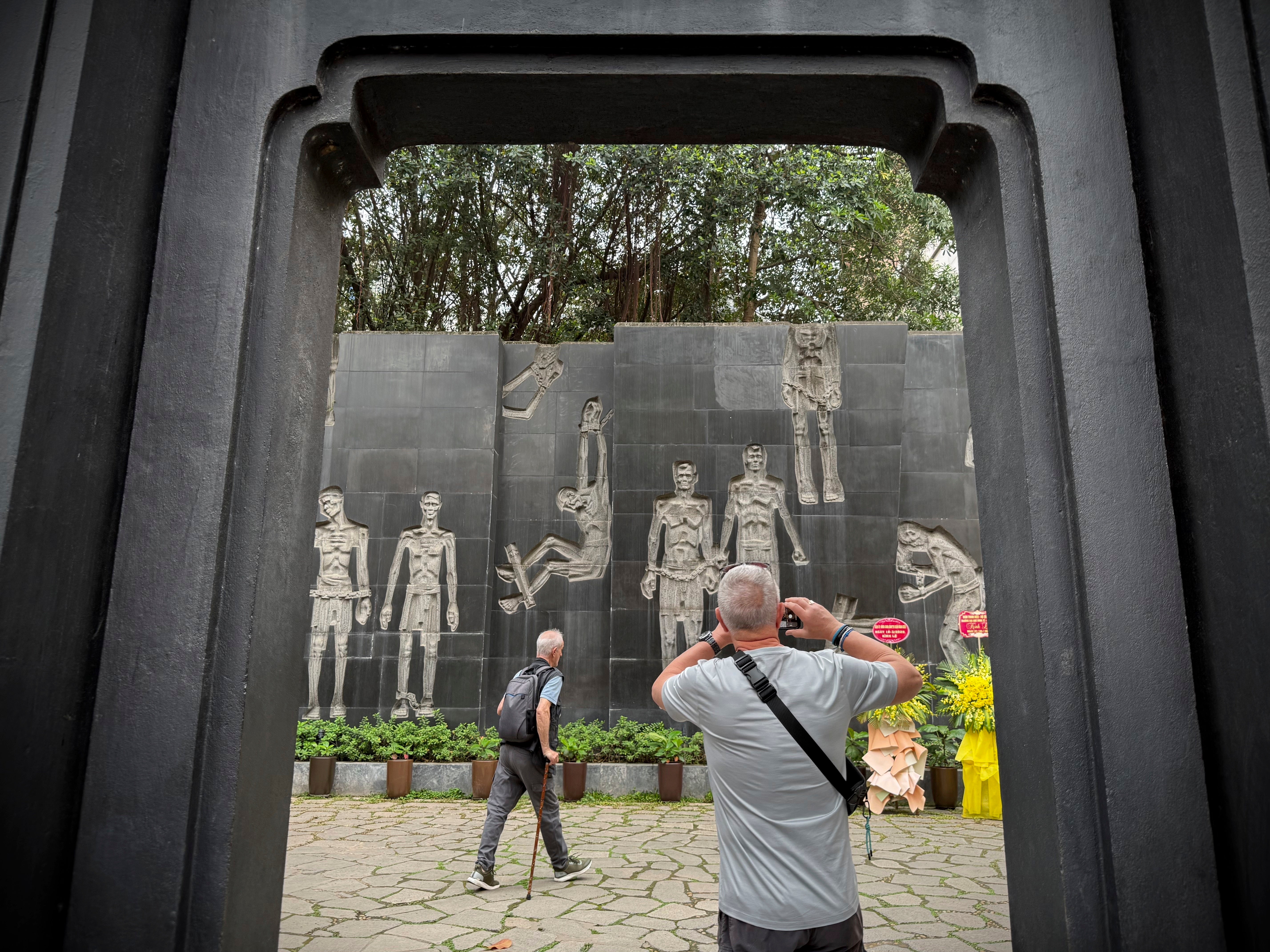 A tourist takes photos of a mural at the Hoa Lo Prison museum in Hanoi