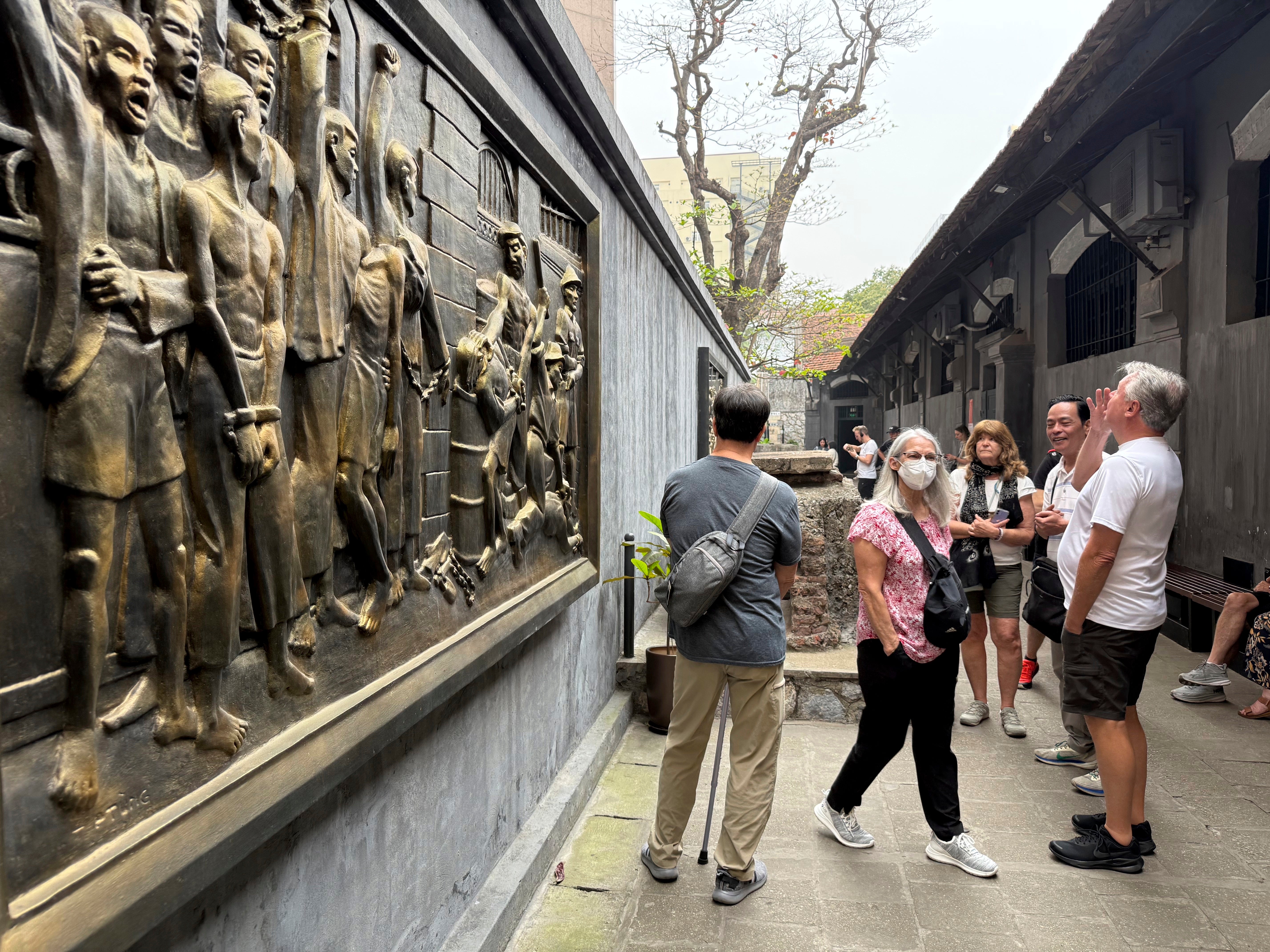 Tourists look at a mural at the Hoa Lo Prison museum in Hanoi