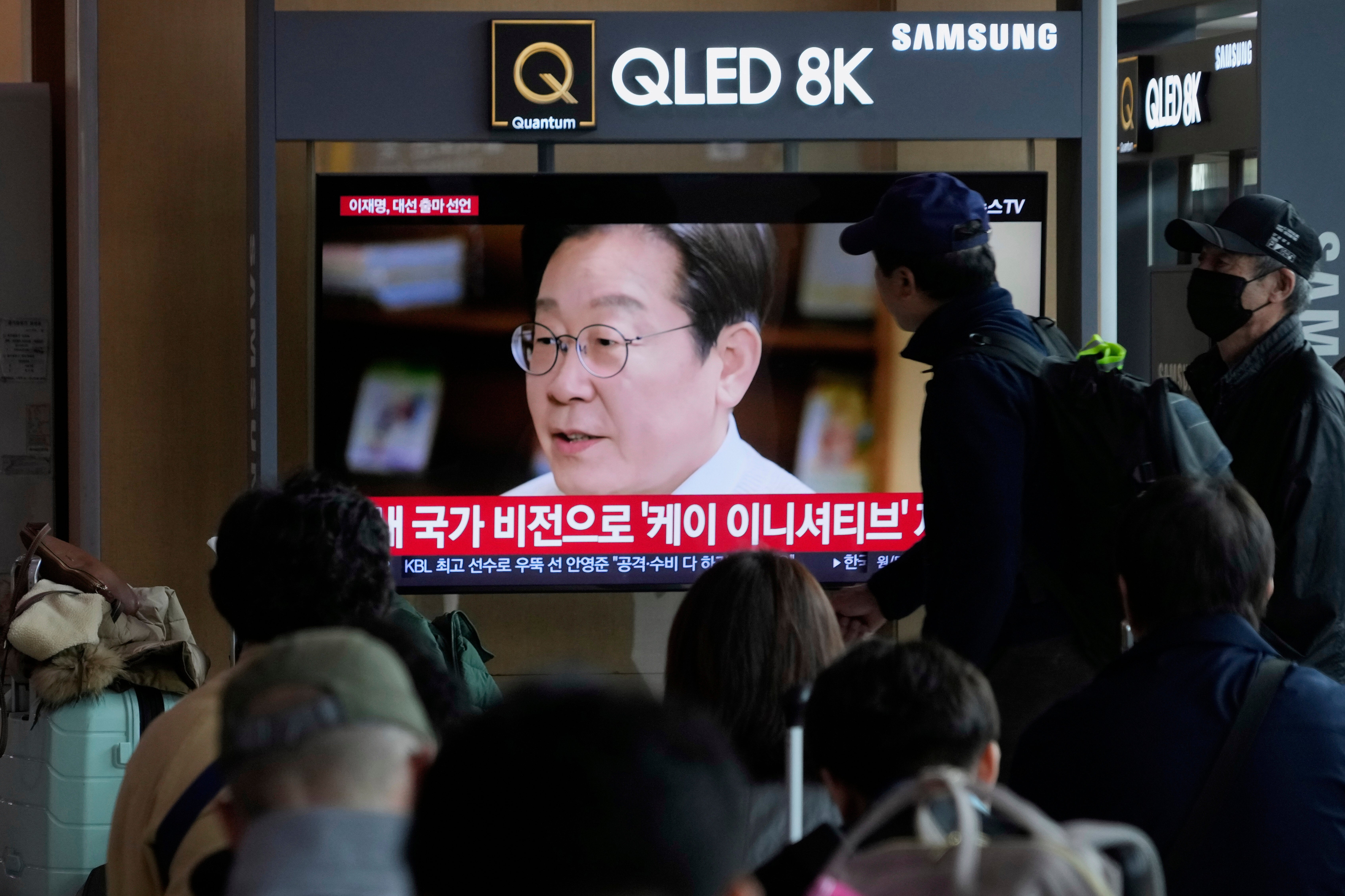 People watch a TV screen showing former South Korea's main opposition Democratic Party leader Lee Jae-myung announces his presidential bid via a video message at the Seoul Railway Station in Seoul, South Korea