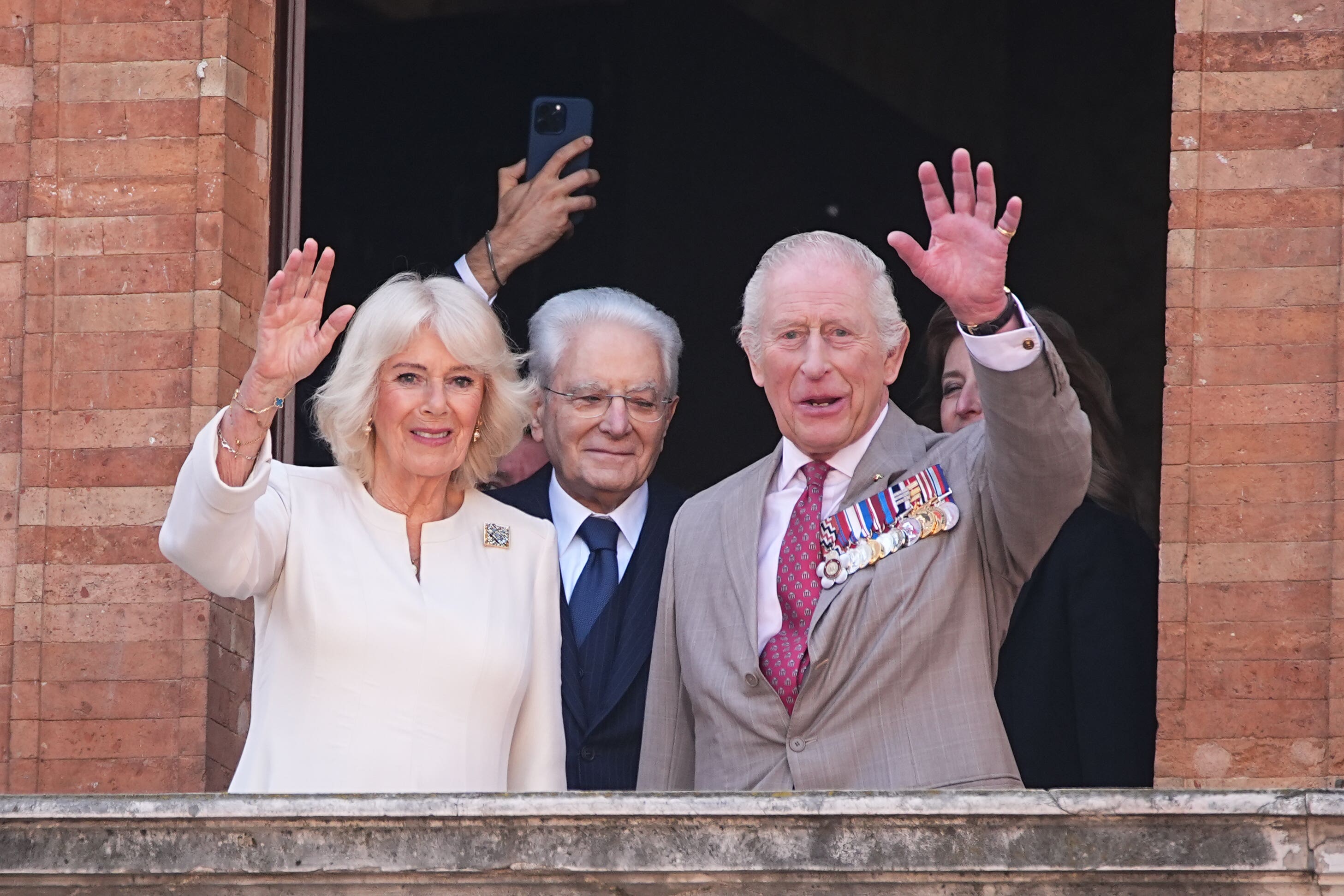 The King and Queen wave from a balcony in the Piazza del Popolo in Ravenna on the last day of the four-day state visit to Italy (Aaron Chown/PA)