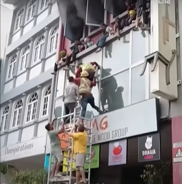 Children are seen sitting on a ledge trying to escape the fire at their cooking school. Screengrab