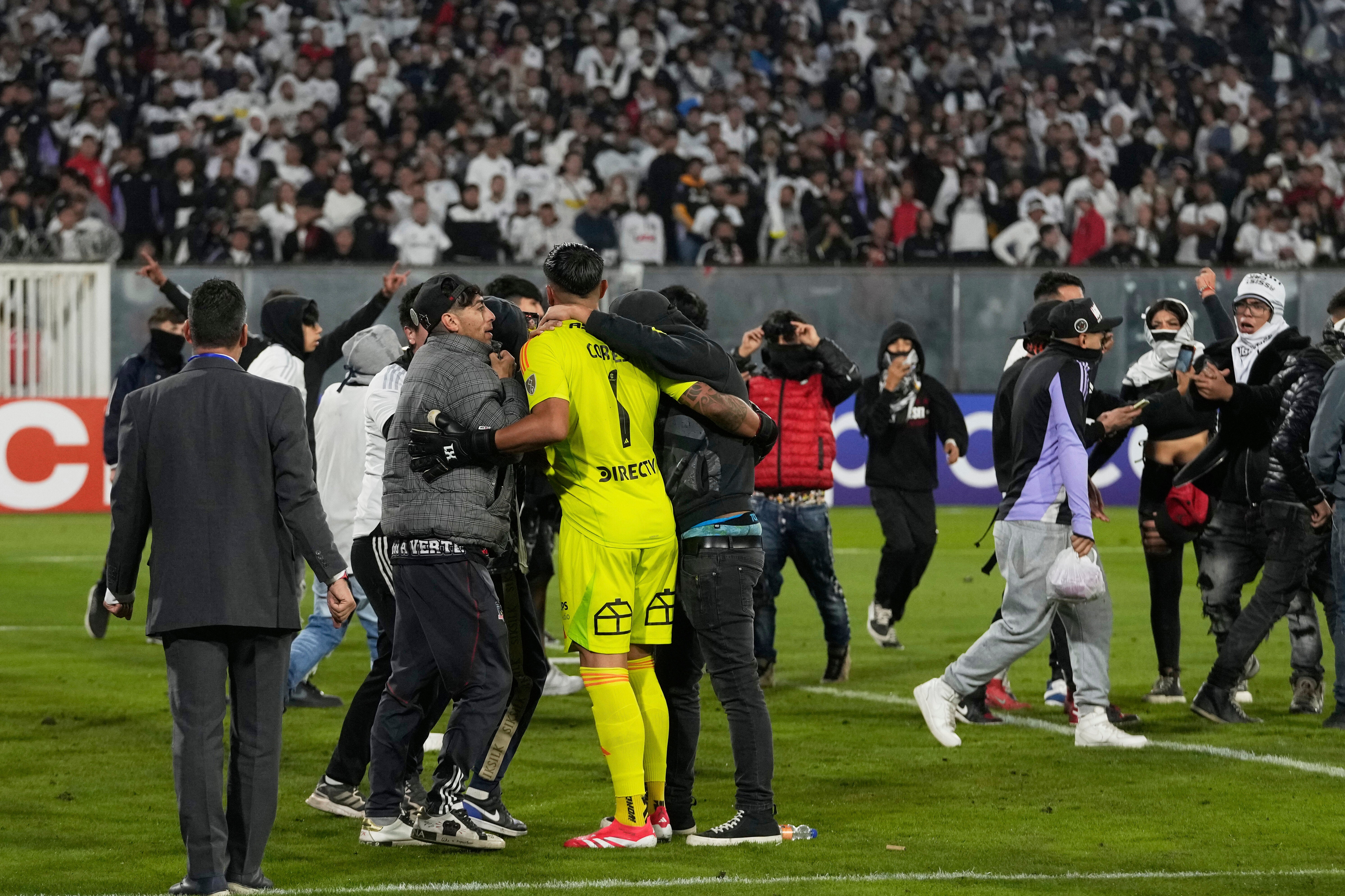 Goalkeeper Brayan Cortes of Chile's Colo Colo confronts fans who invaded the field during a Copa Libertadores Group E soccer match against Brazil's Fortaleza at the Monumental stadium in Santiago, Chile, Thursday, April 10, 2025. (AP Photo/Esteban Felix)