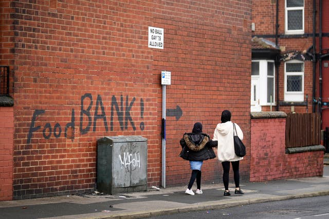<p>A sign painted on the side of a house directs people to a local food bank in Leeds, England</p>