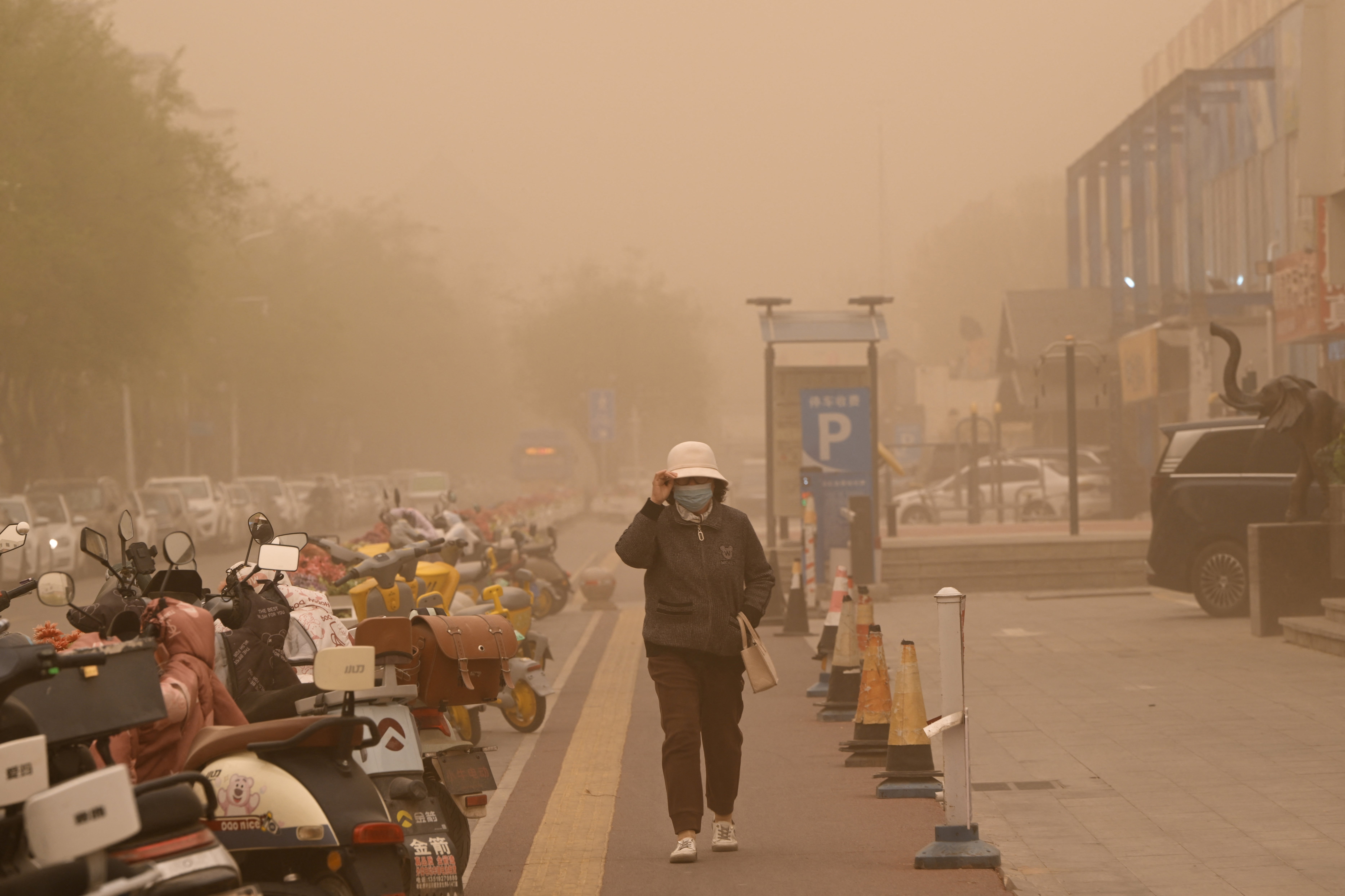 A woman walks on a sidewalk during a sandstorm in Yinchuan in northern China's Ningxia region