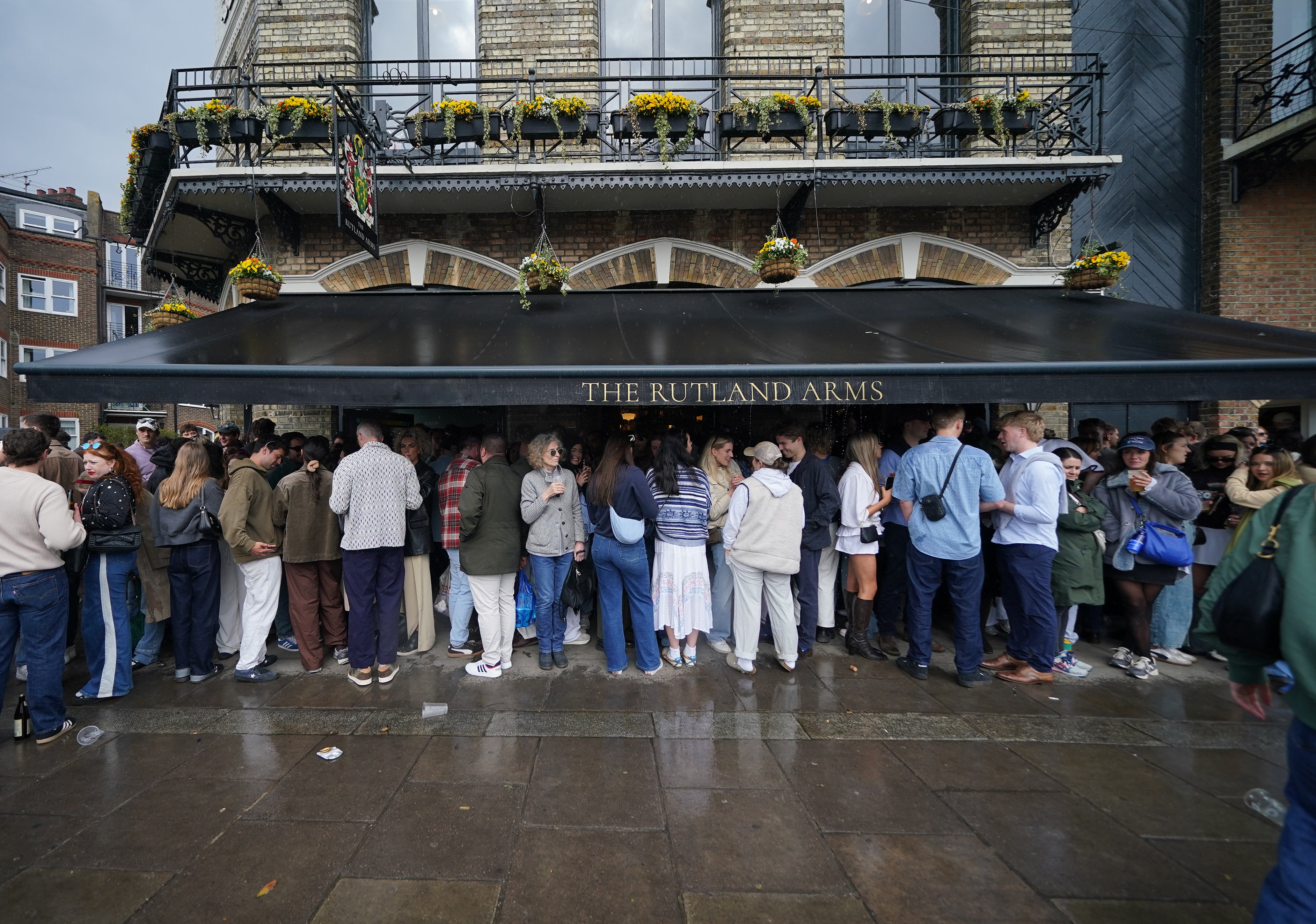 People sheltering from the rain underneath a pub awning in Hammersmith, London on Sunday
