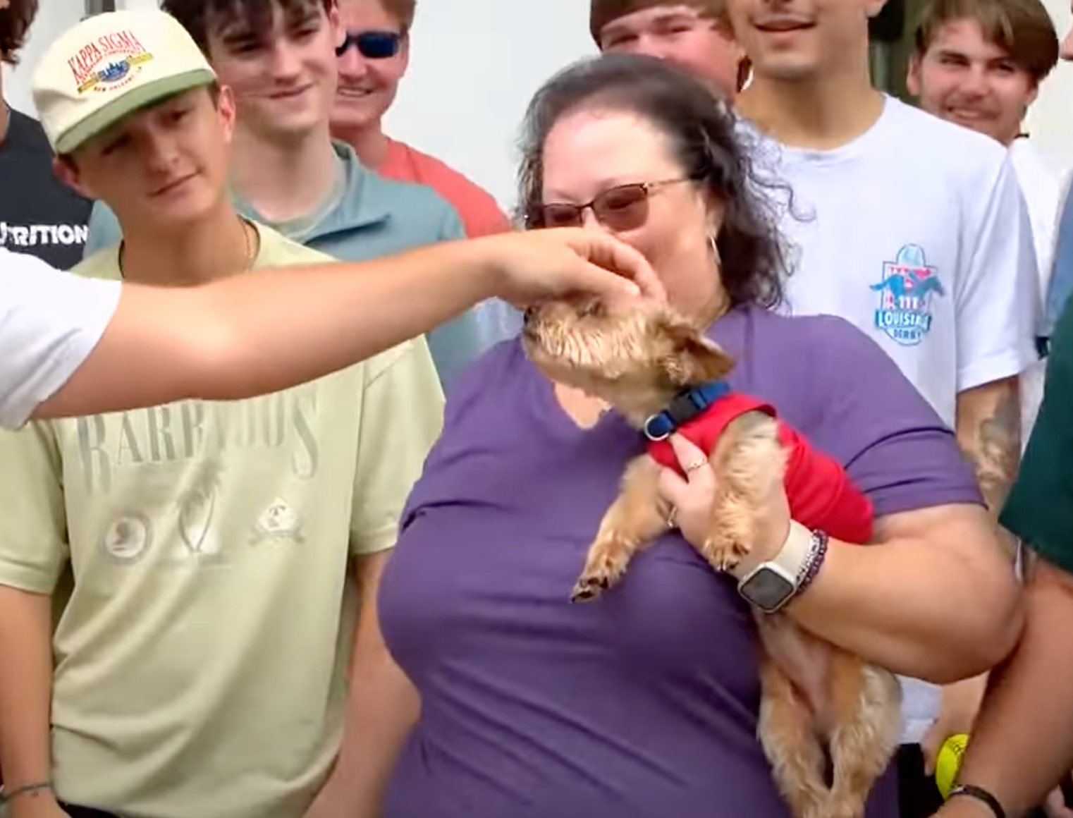 A member of the Kappa Sigma fraternity reaches out to pet Kingston, a Yorkie who disappeared from his Lake Charles home in 2020 and traveled 300 miles to eventually end up at the University of Southern Mississippi campus. Debbie LaFleur, Kingston's owner, holds the dog after the fraternity brothers arranged to reunite the two.