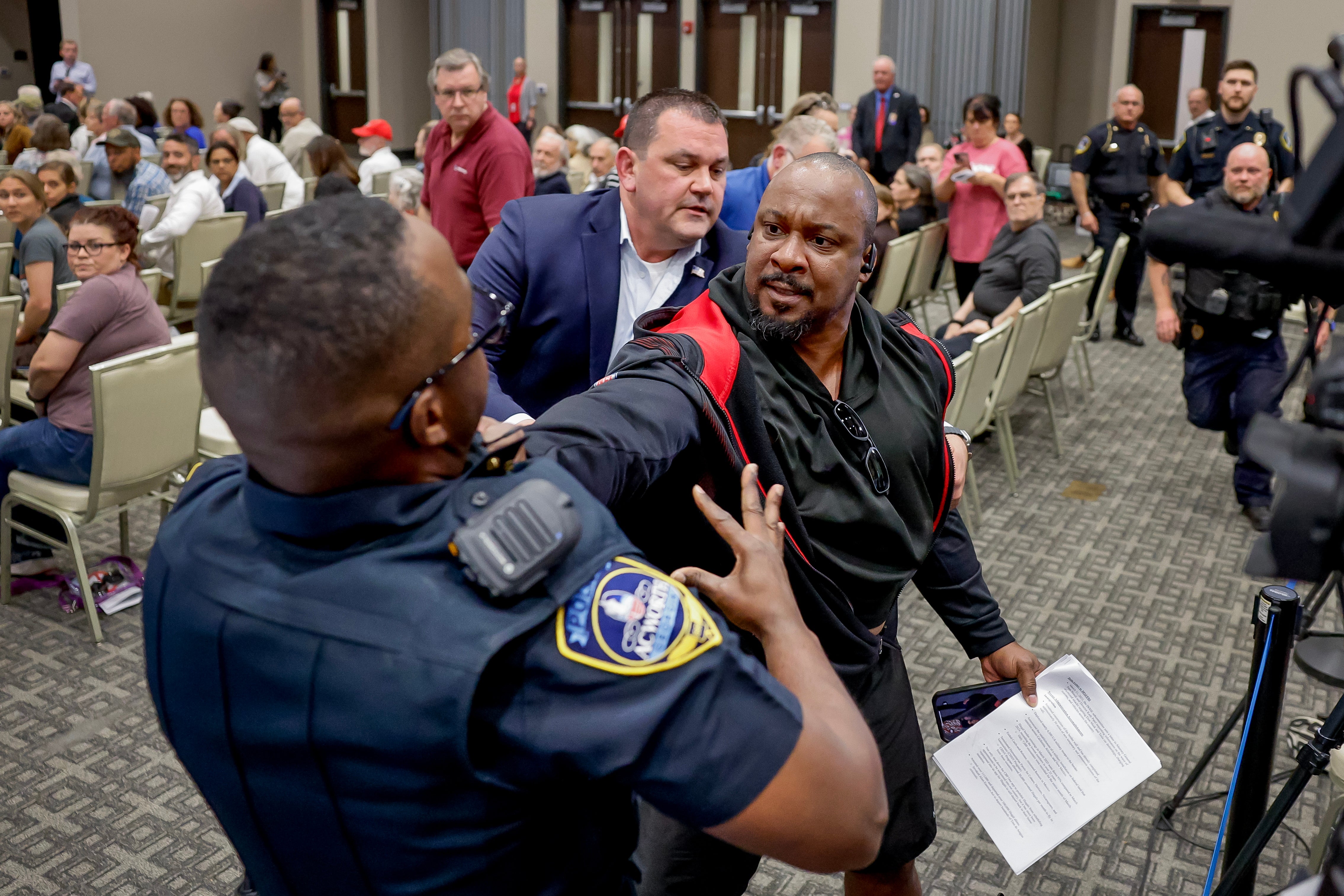 A protester resists being removed by an Acworth Police officer as Republican Representative Marjorie Taylor Greene takes part in a town hall