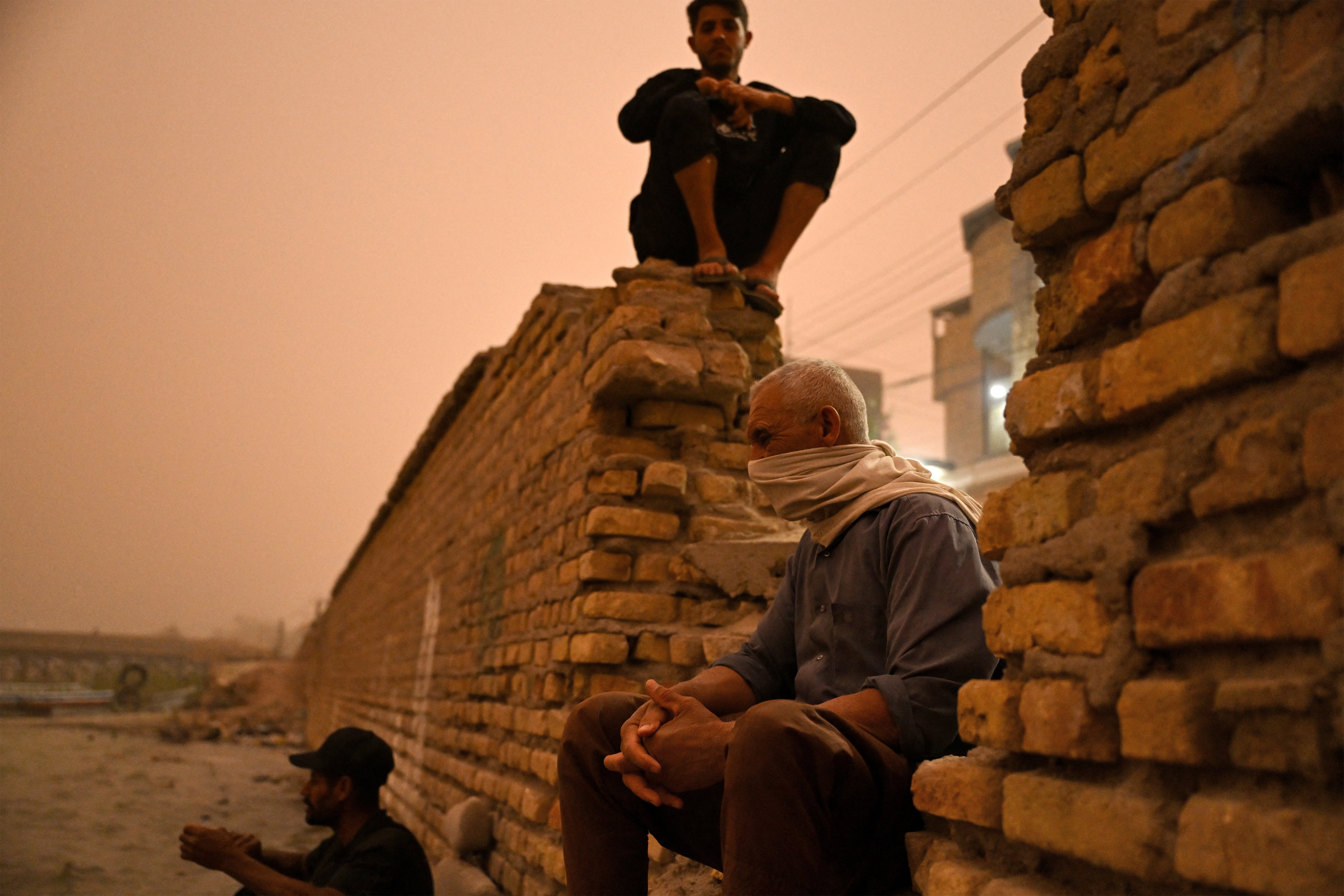 A man sits along the bank of the Shatt al-Arab waterway amid a massive dust storm in Iraq's southern city of Basra on 14 April 2025. Around 1,500 people were sent to hospitals with respiratory problems on 14 April as a storm hit central and southern Iraq, health officials said