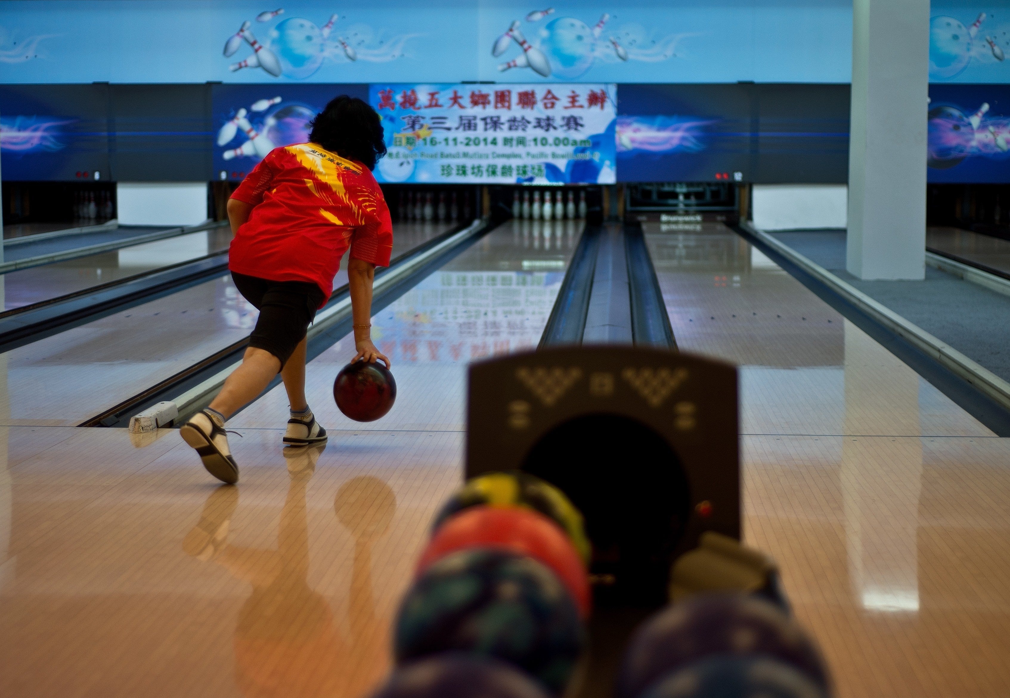 A woman rolls the ball as she plays a round of ten-pin bowling