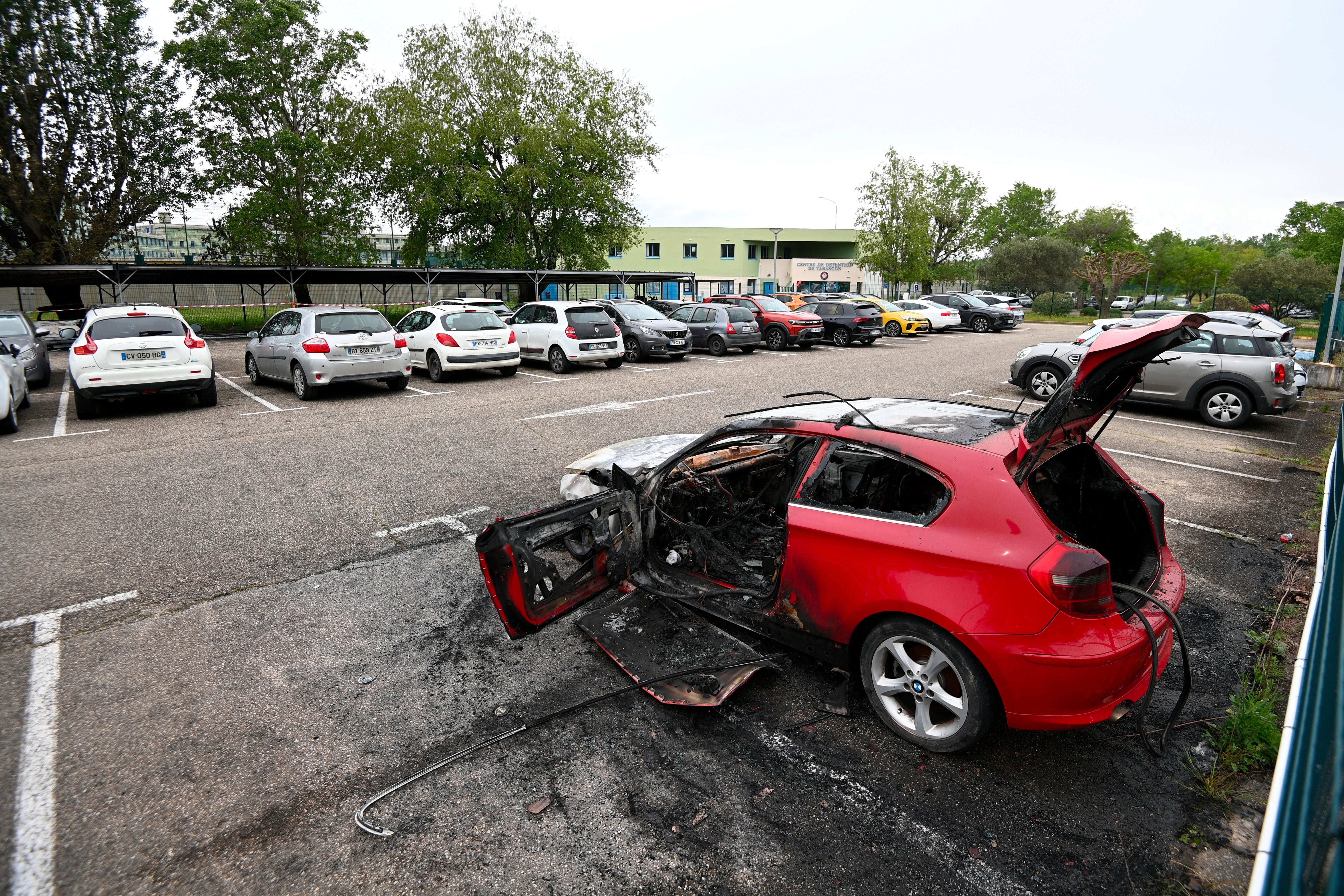 This photograph shows a burned car in front of the Tarascon prison in Tarascon, southern France, after 3 cars were set on fire the previous night in its parking lot. Assailants targeted cars and a building lobby linked to prison staff in France overnight, the authorities said on April 16, the latest in a series of such attacks