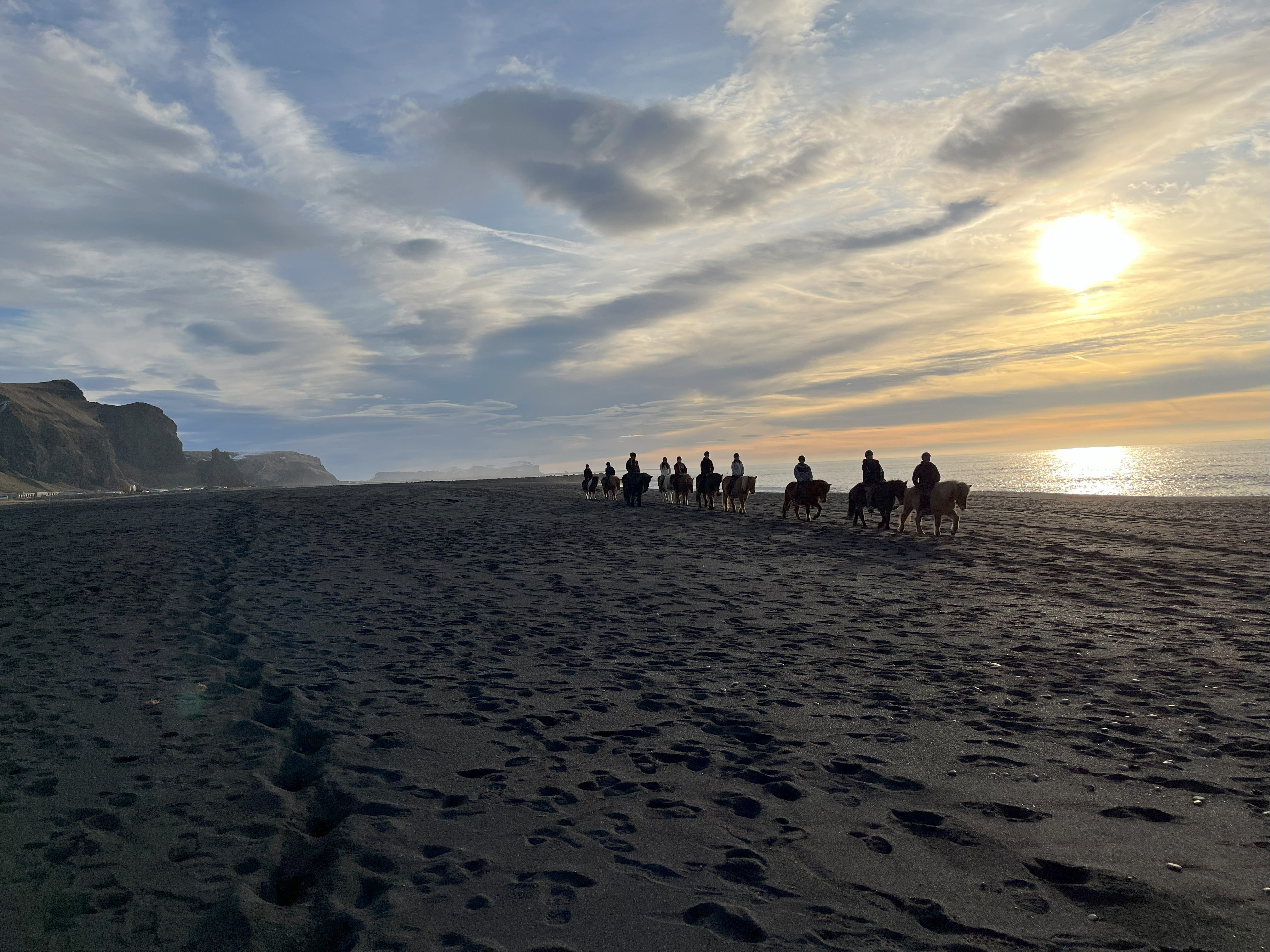 As sunrise arrives, Icelandic horses trot across the black sand at Reynisfjöru beach