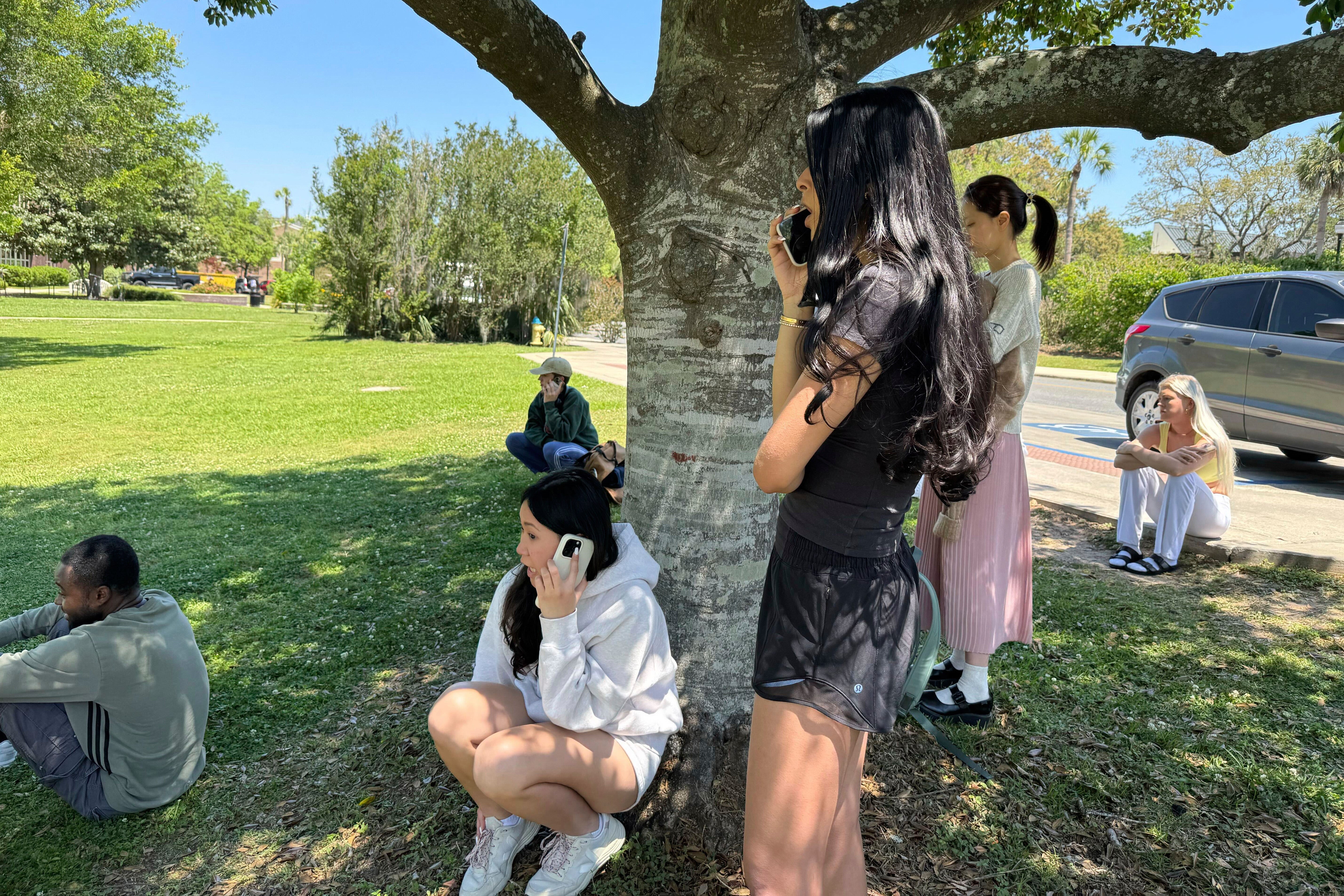 Students are pictured on the phone as they await news following the active shooter alert