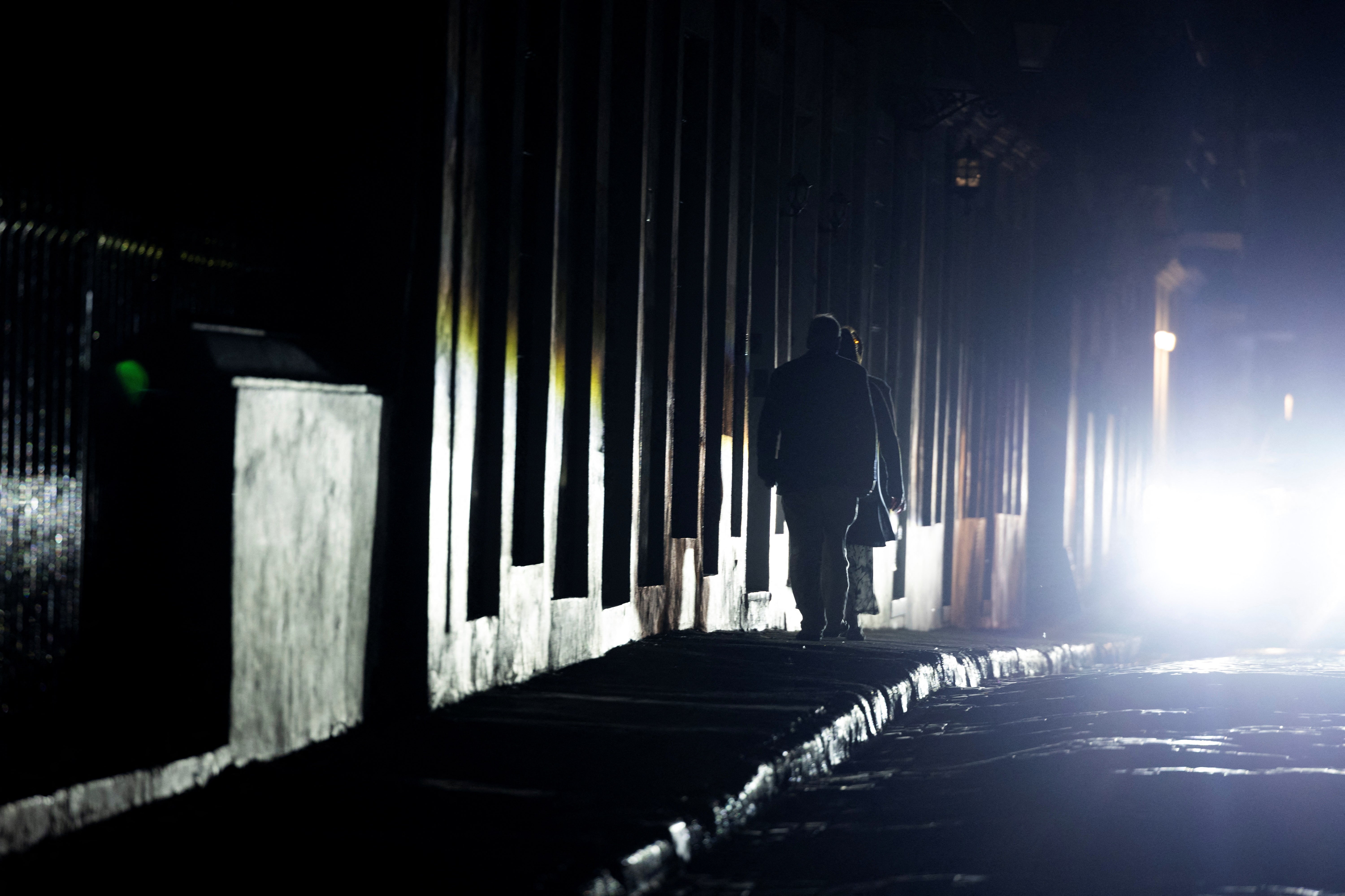 People walk down a dark street in San Juan, Puerto Rico after the island was hit with a massive power outage