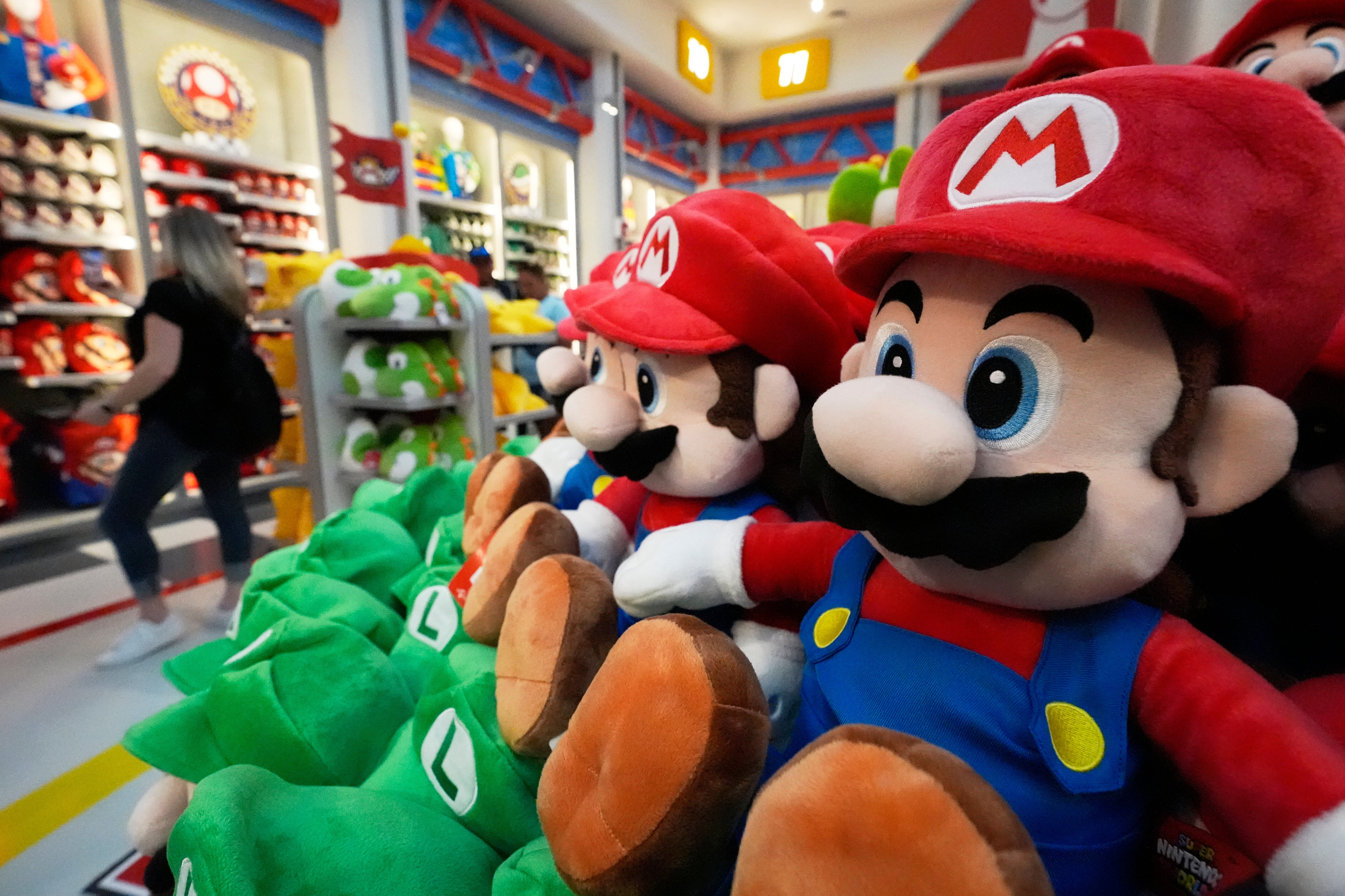 A shopper looks over merchandise for sale in a gift shop at Super Nintendo World at Epic Universe Theme Park at Universal Resort Orlando