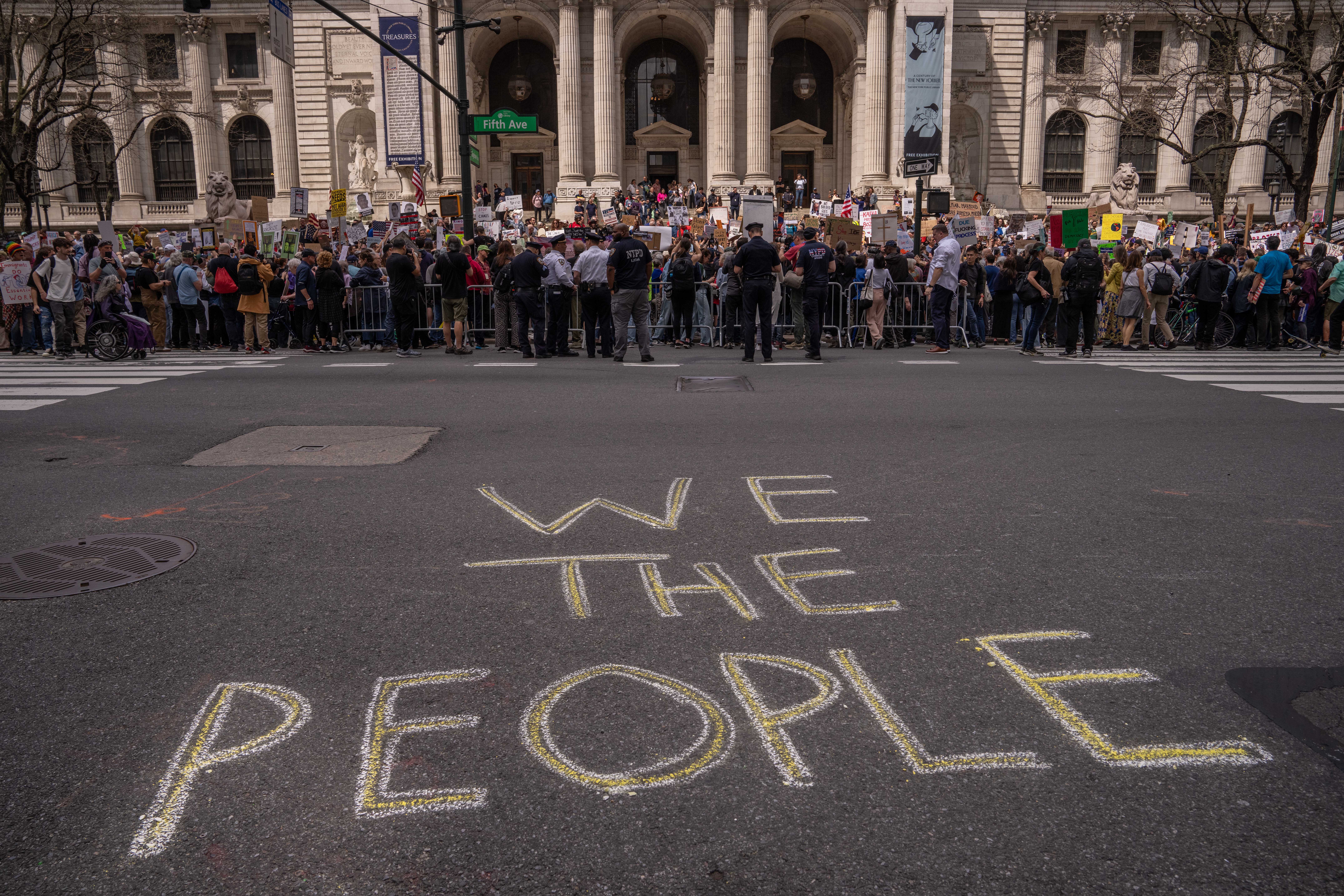 Protesters line up along New York’s Fifth Avenue in front of the chalk-drawn words ‘We the People’ written on the street