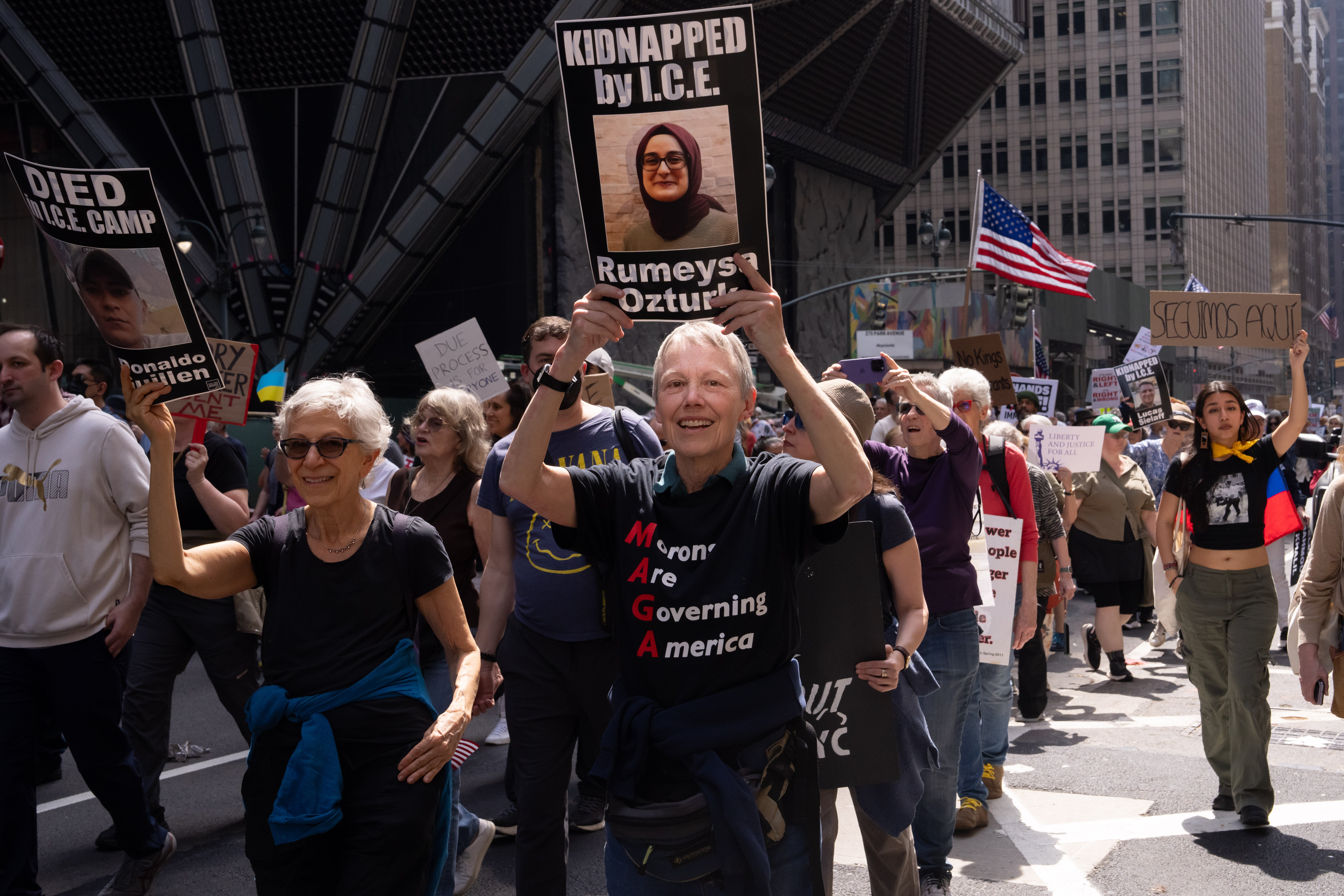A protester holds up a sign featuring a photo of a Tufts doctoral student who is being held in ICE custody