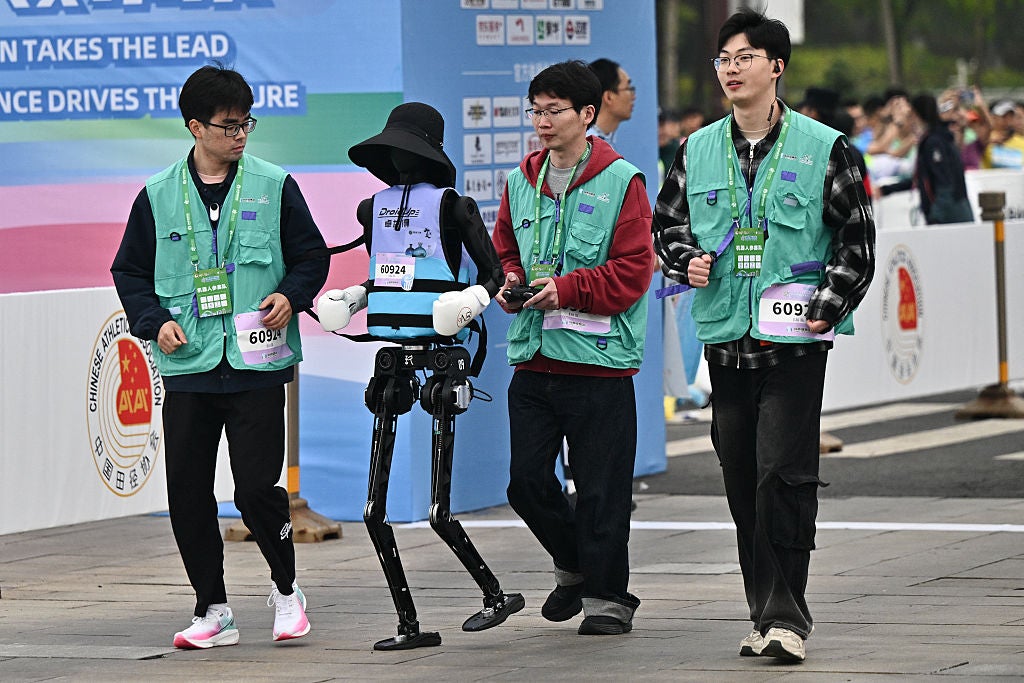A robot and its engineers run in the humanoid robot half-marathon