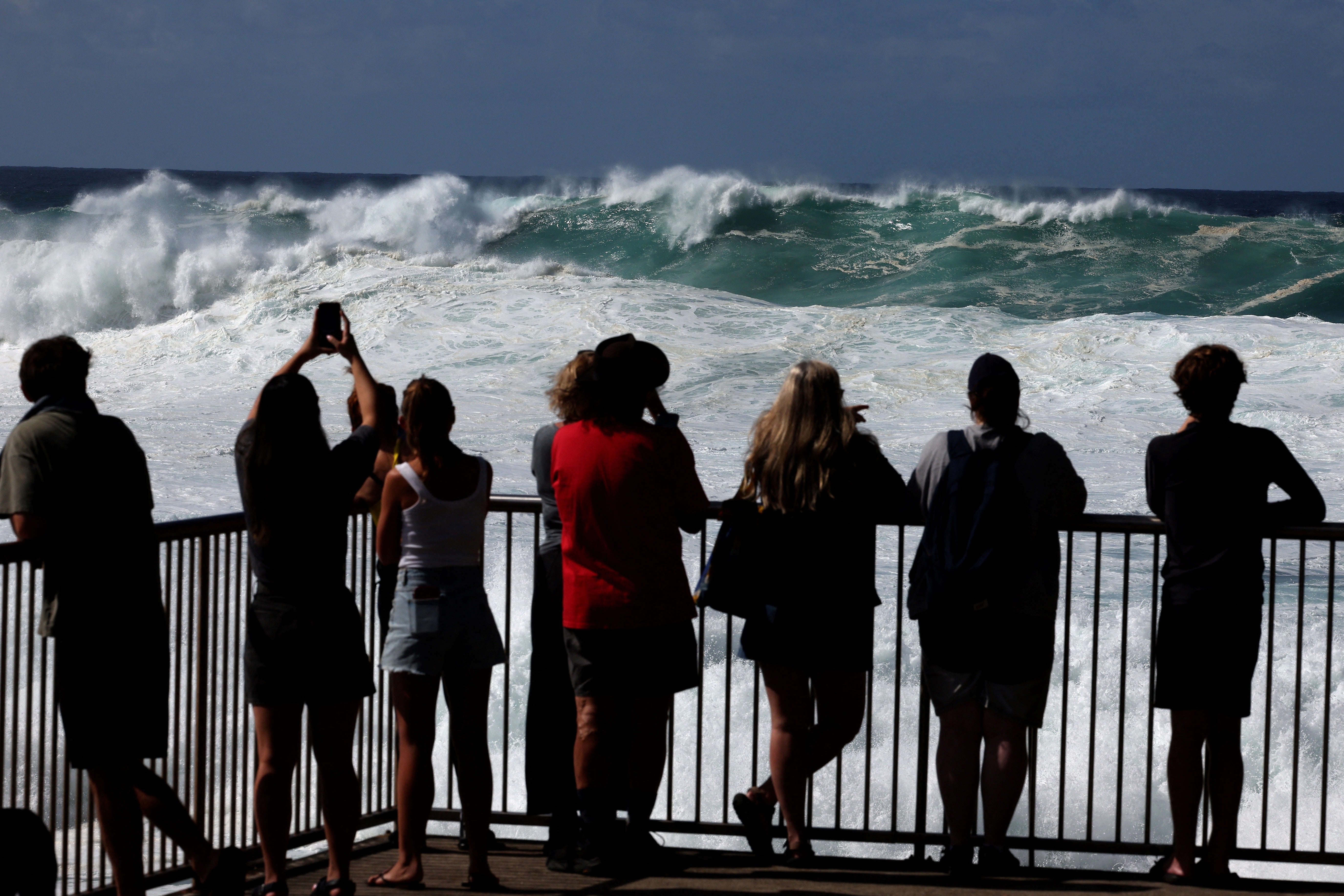 Visitors watch large waves crash against a rock on Bronte Beach in Sydney