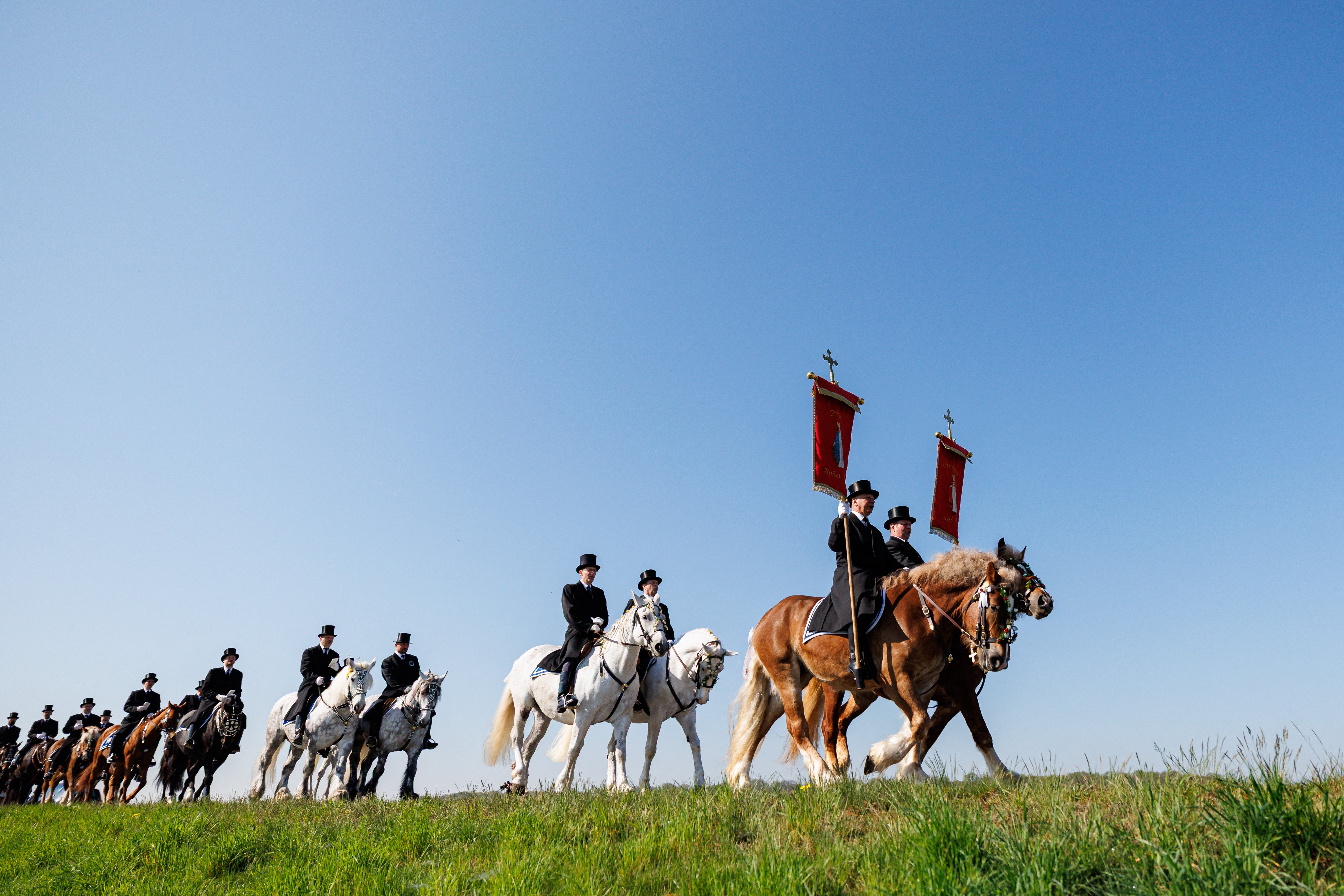 Sorbian horsemen dressed in traditional black attire sing as they ride on decorated horses during the Sorbian Easter horseback procession on Easter Sunday in Ralbitz-Rosenthal, eastern Germany