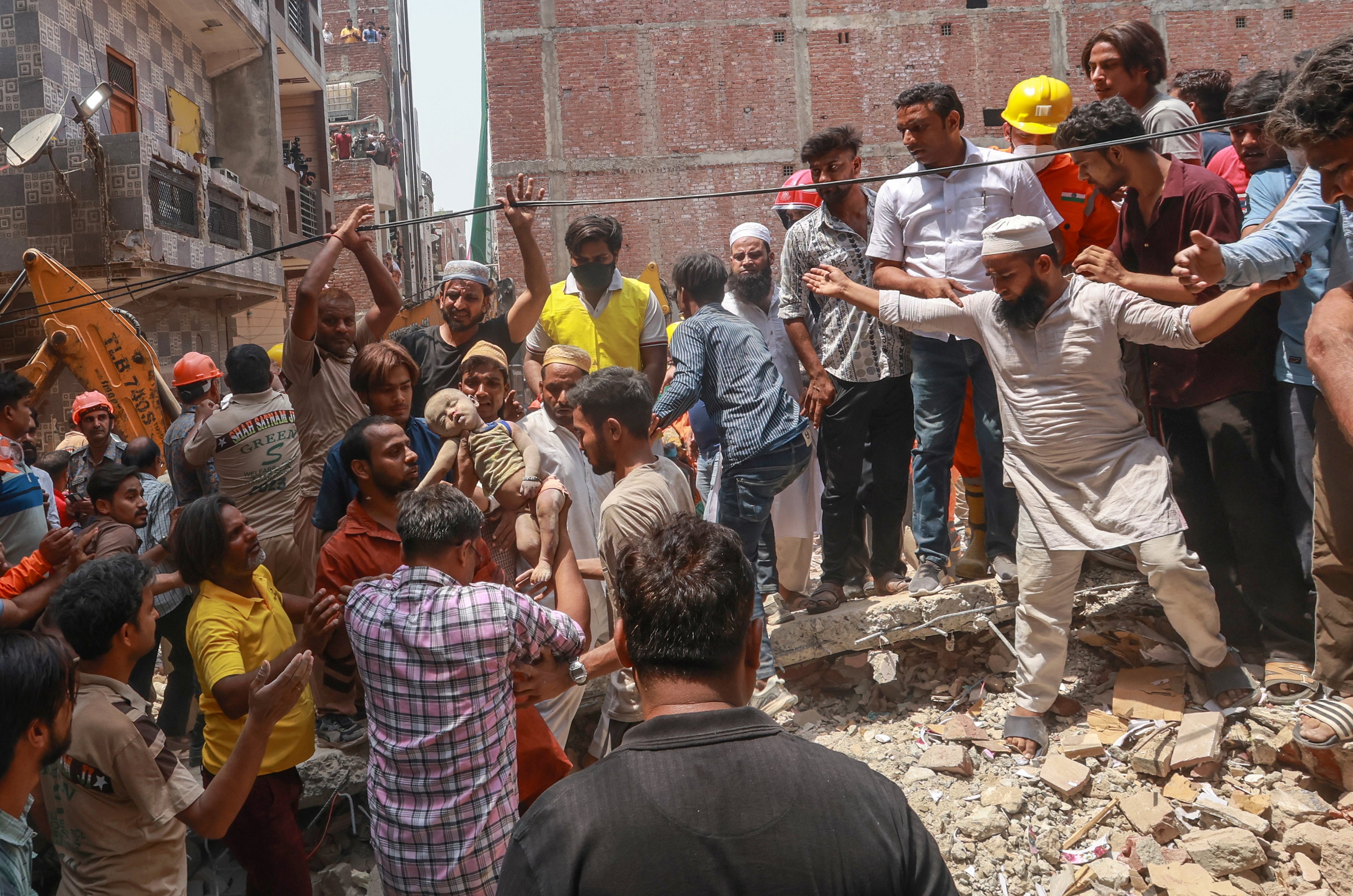 National Disaster Response Force (NDRF) personnel extract an infant victim from the rubble