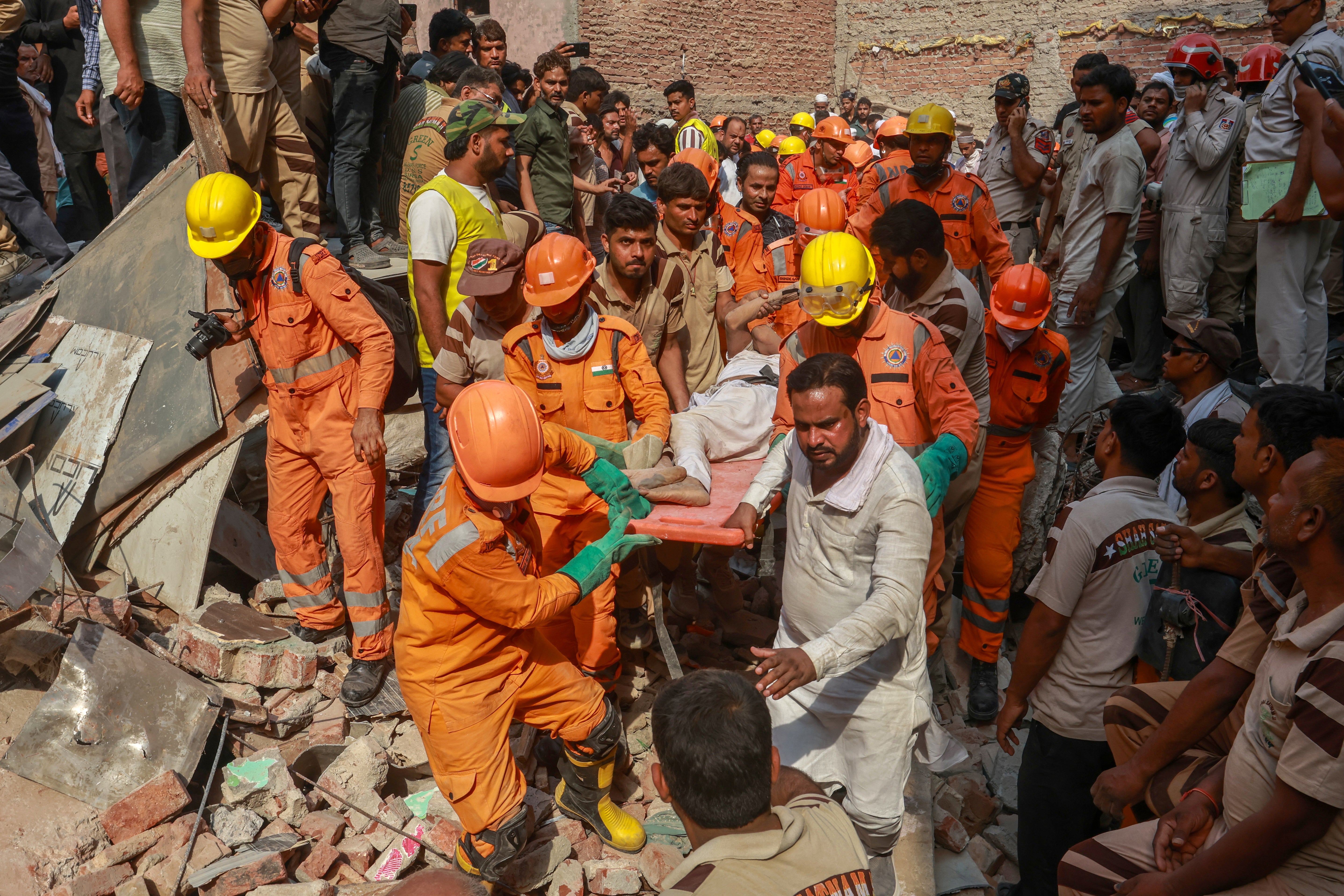 National Disaster Response Force (NDRF) personnel carry a person on a stretcher after extracting them from the rubble