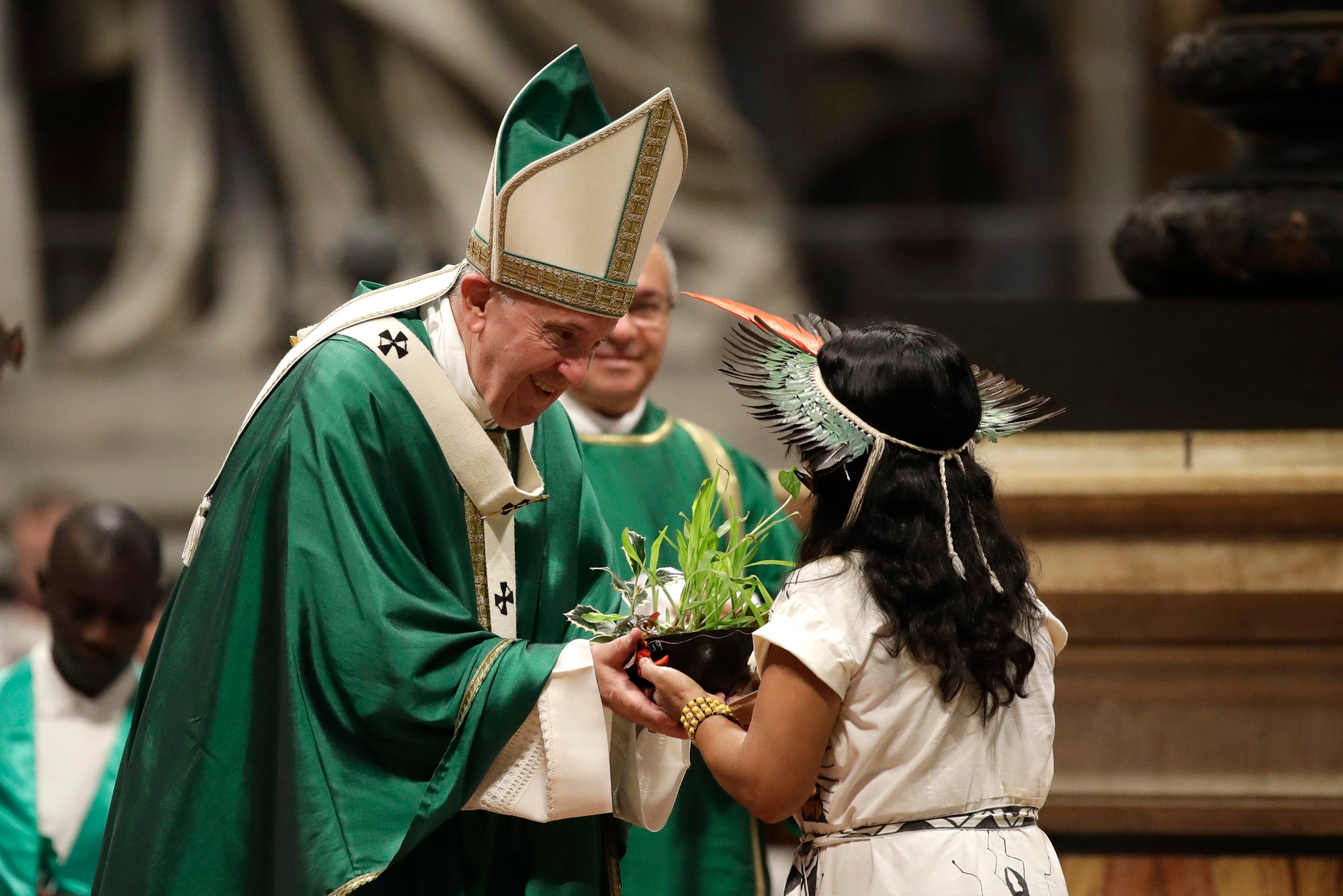 An Amazonian indigenous girl gives Pope Francis a plant during the offertory of a Mass for the closing of Amazon synod in St. Peter's Basilica at the Vatican, Sunday, October 27, 2019