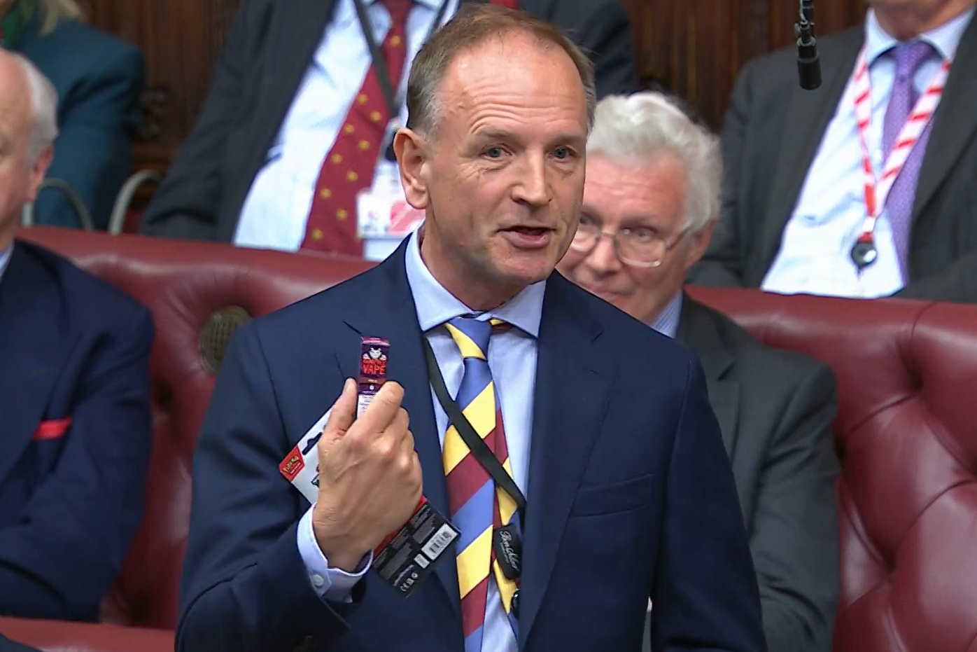 Lord Stevens of Birmingham, Cancer Research UK’s chairman, holds up a vape and a packet of Pokemon cards which he said were displayed near each other in a newsagent (House of Lords/PA)