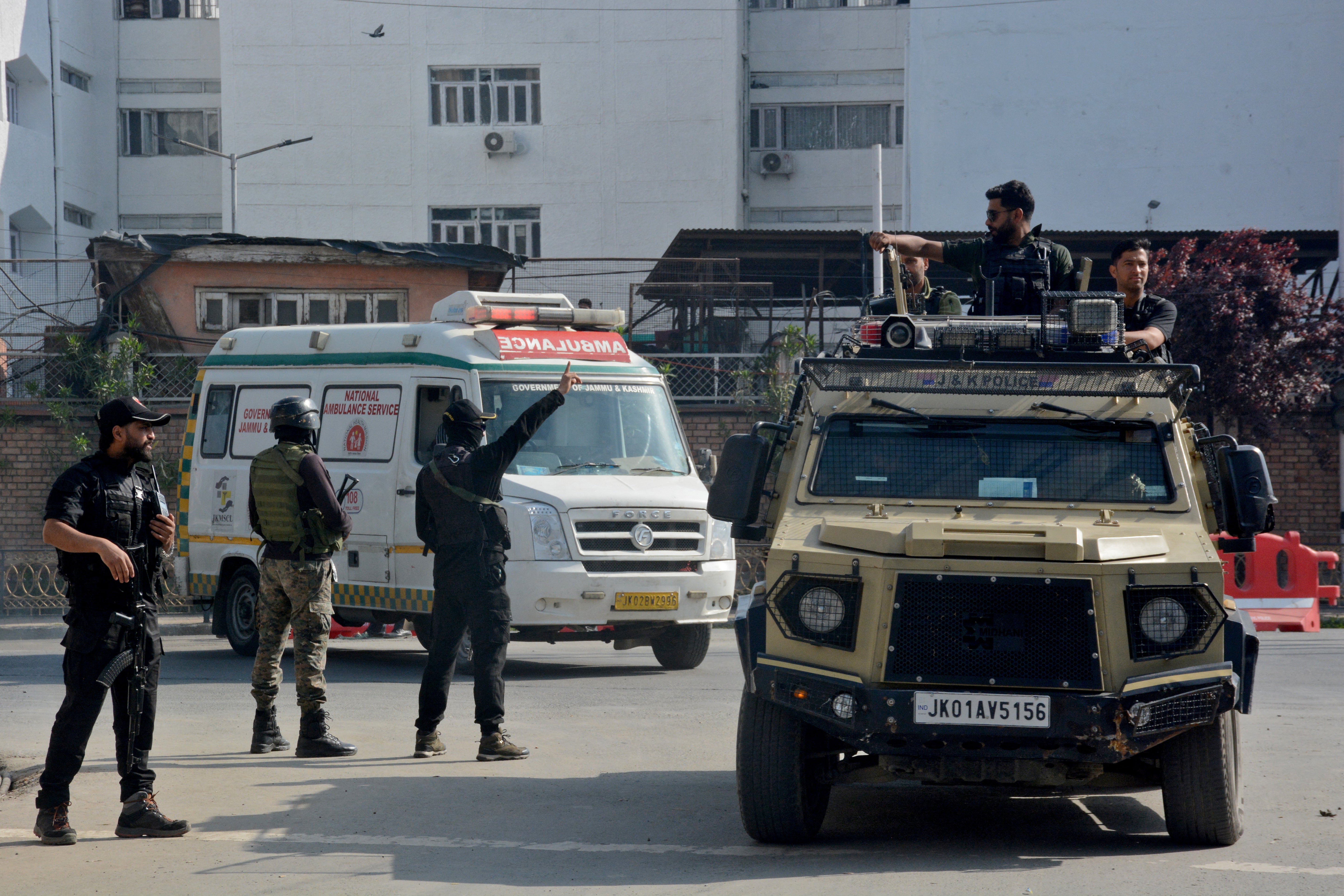 Indian security forces personnel escort an ambulance carrying the bodies of tourists who were killed in a suspected militant attack near Pahalgam, outside the police control room in Srinagar