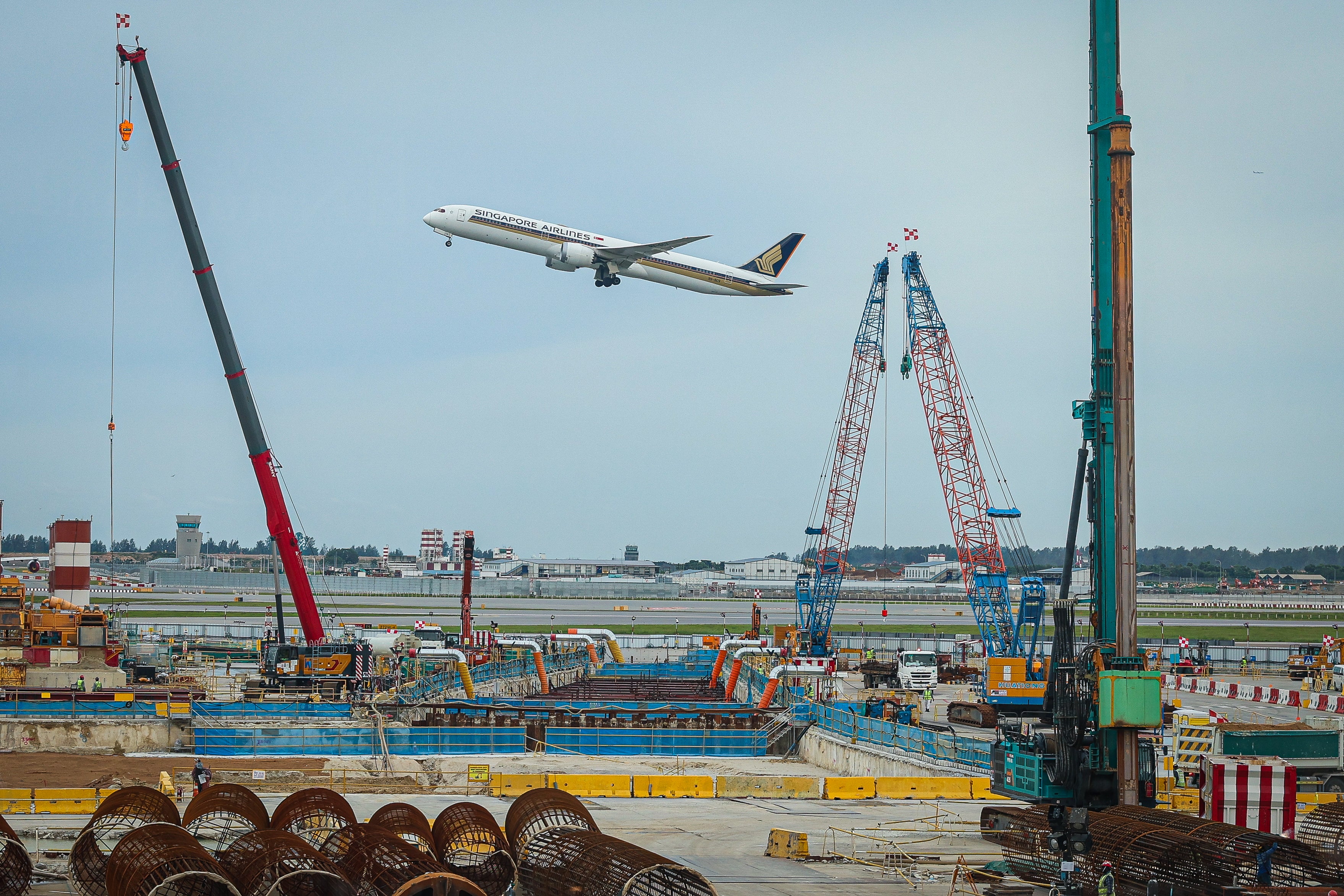 <p>Representative: A Singapore Airlines plane flies past a construction site at Terminal 2 of Changi Airport on 14 April 2025 in Singapore</p>