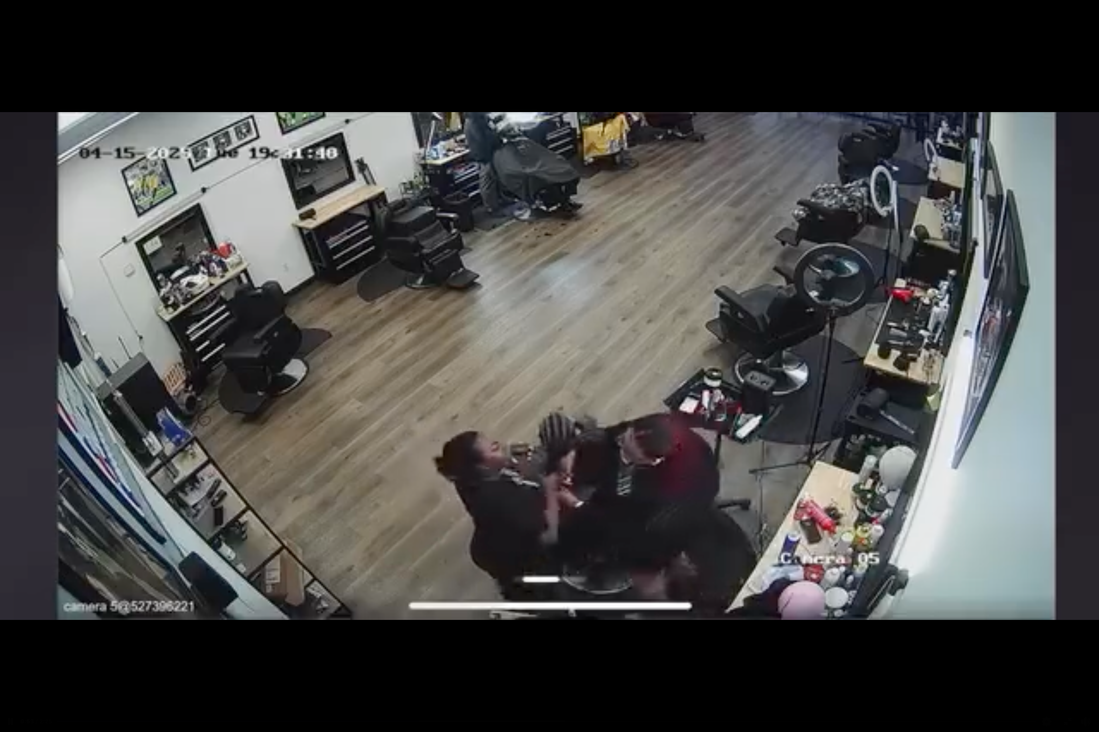 The mom pulls the girl's hair toward her and away from the stylist's scissors