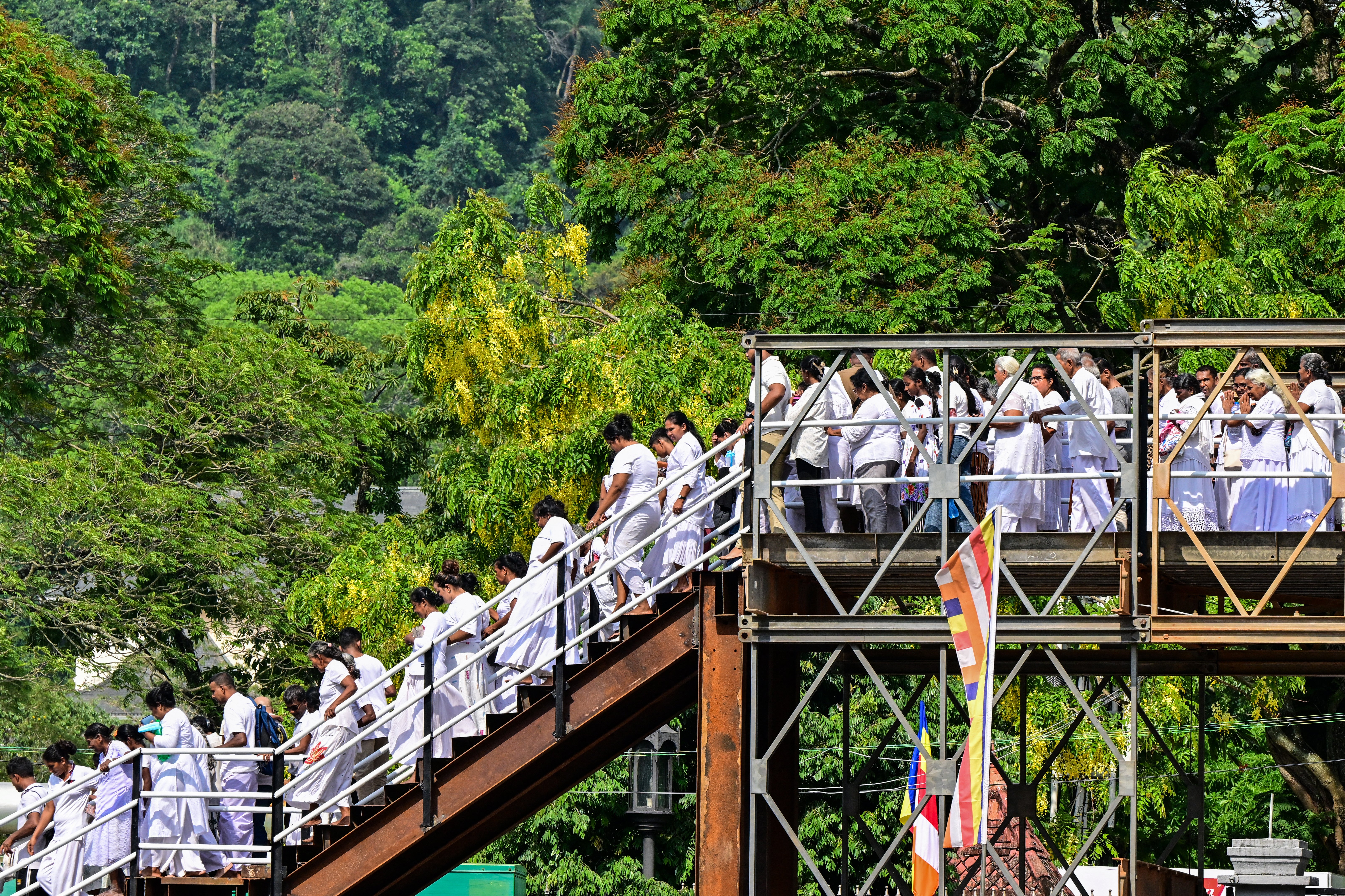 Buddhist devotees stand in queues as they wait to enter the Temple of the Sacred Tooth for a public exhibition of a sacred relic in Kandy on 18 April 2025